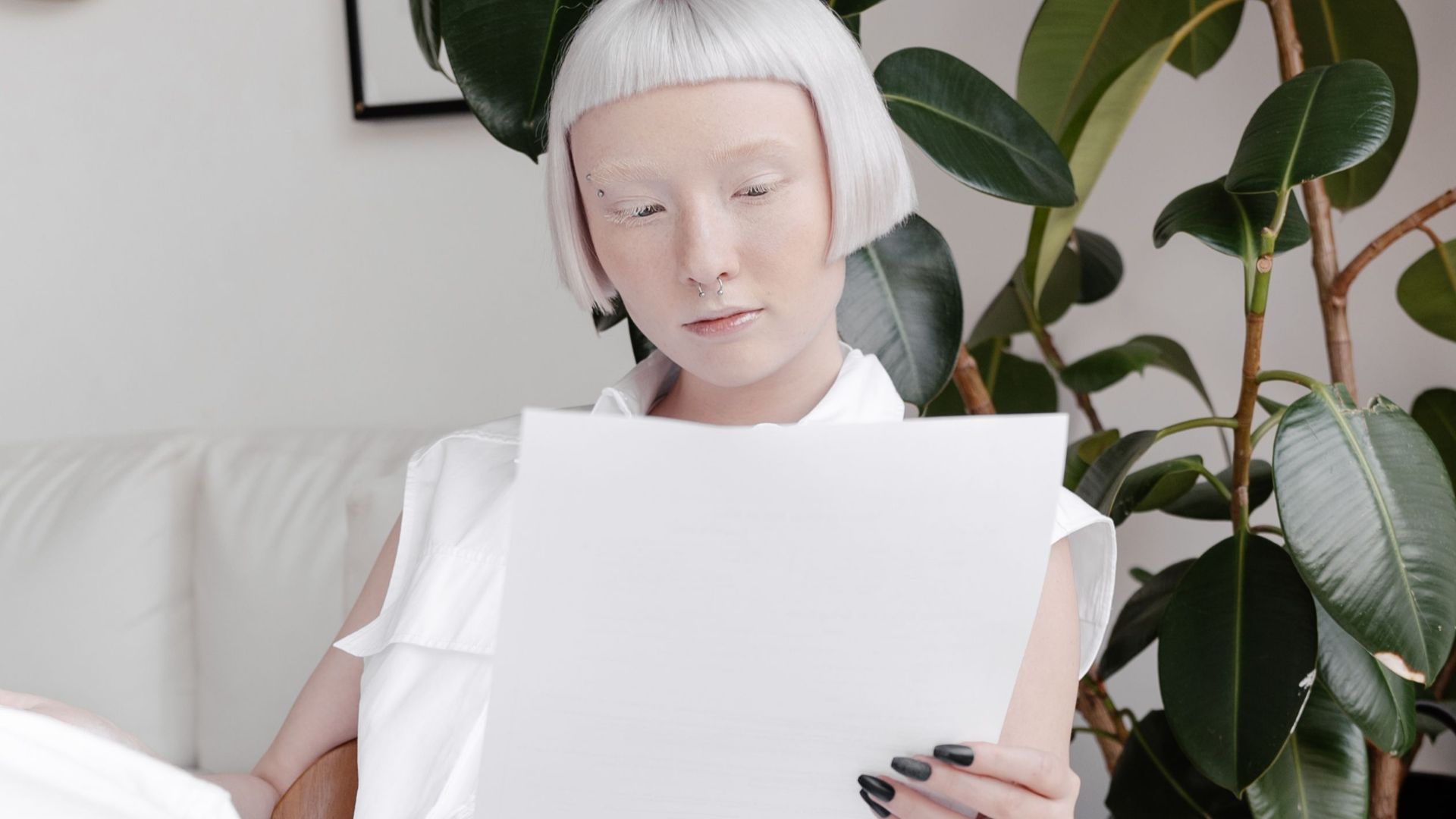 Stylish woman in white reading documents in a contemporary living space.