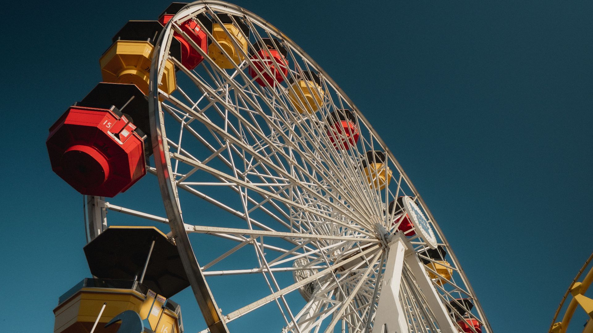 A colorful ferris wheel photographed from a low angle under a clear blue sky.