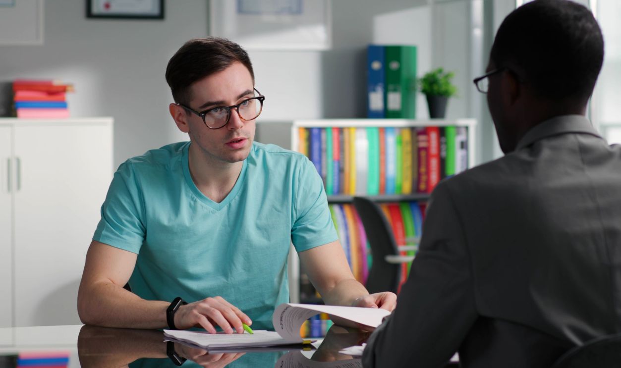 Male customer read agreement and ask manager questions. Young man and attorney discuss contract details