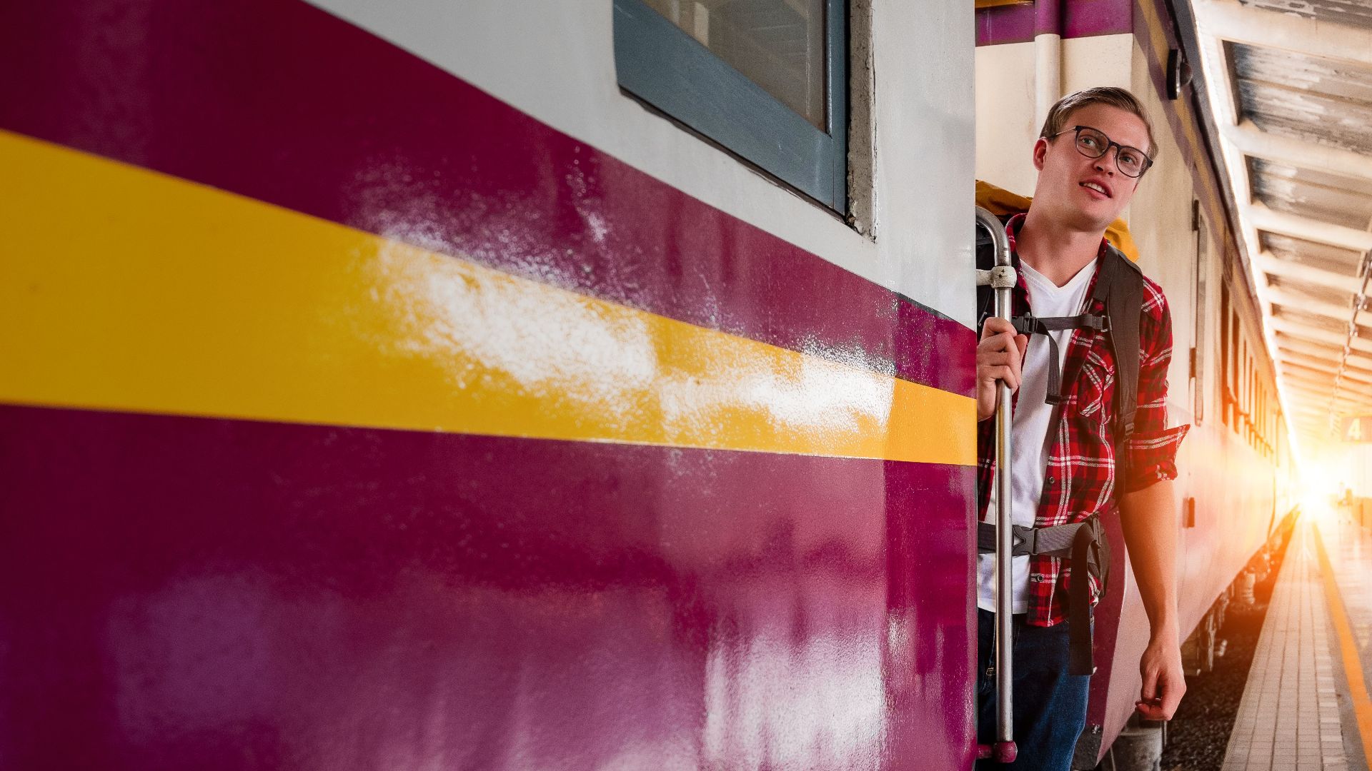 A young man with a backpack prepares to board a train at an urban station, capturing the spirit of travel and exploration.