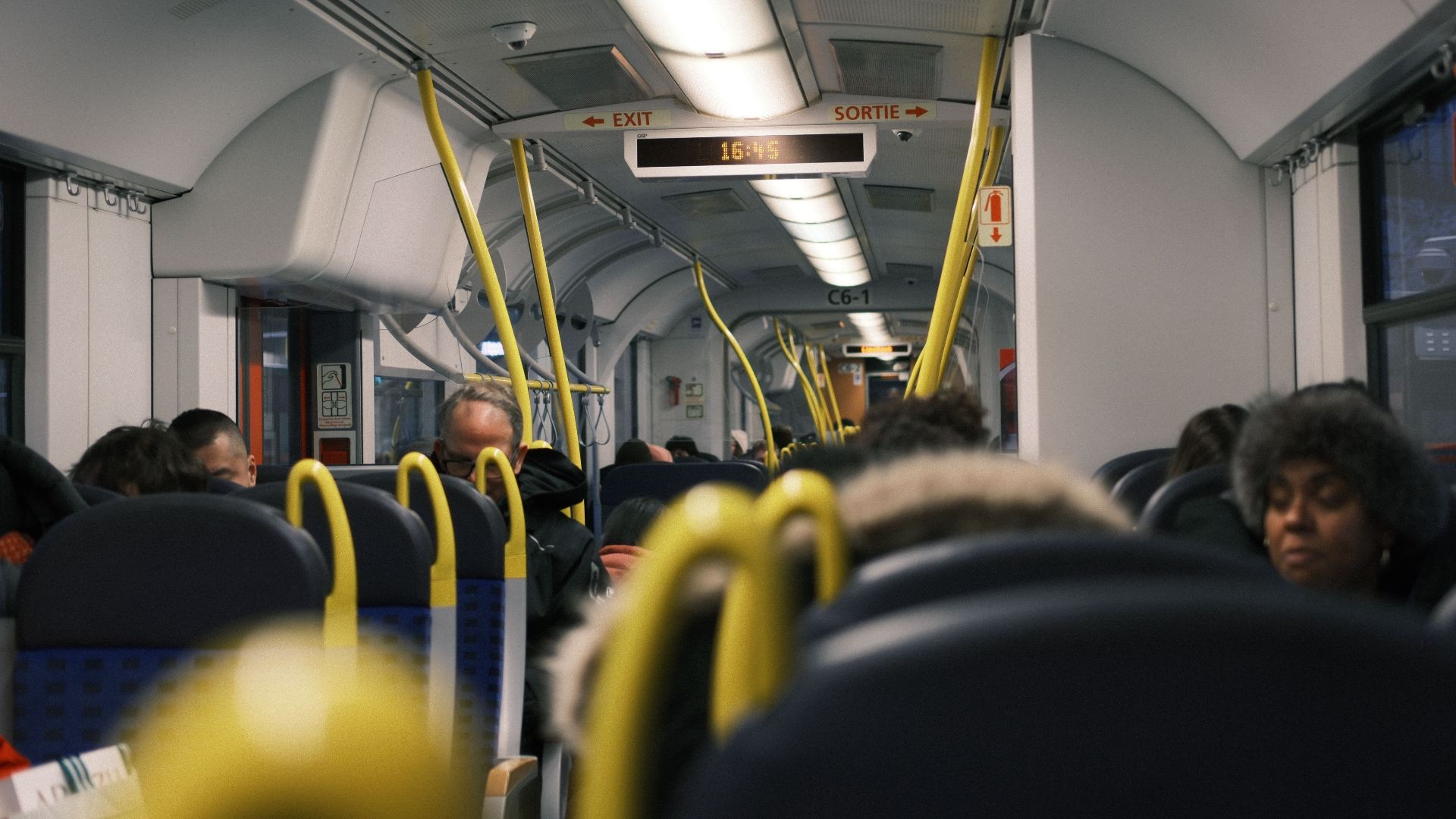 Passengers commuting inside a modern public train during the day.