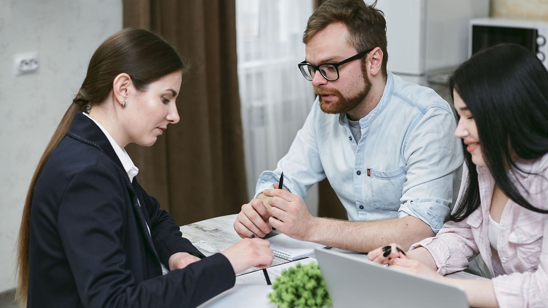 A couple discusses financial documents with their advisor, highlighting investment strategies.