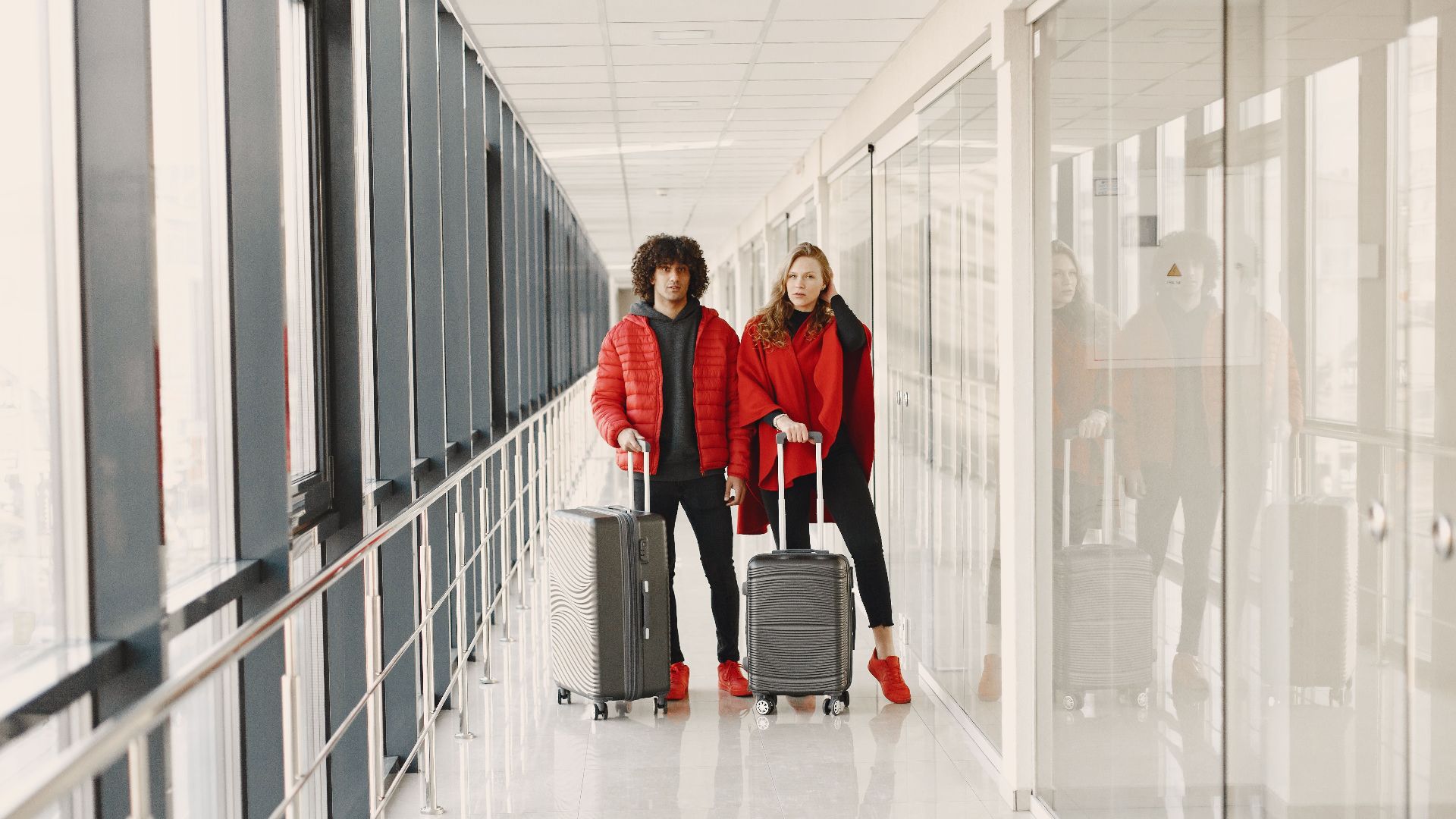 Young couple standing in a hallway with luggage, ready for travel. Bright modern scene.