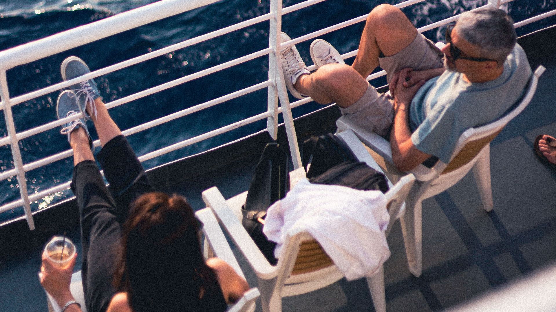 Couple relaxing on a cruise ship deck, enjoying the serene ocean view on a sunny day.