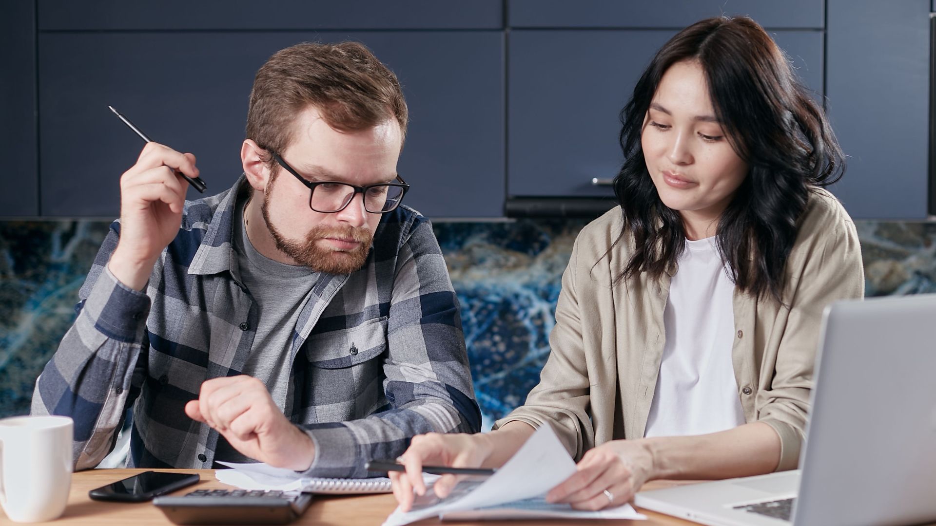 A couple is reviewing and calculating their household bills together at home.