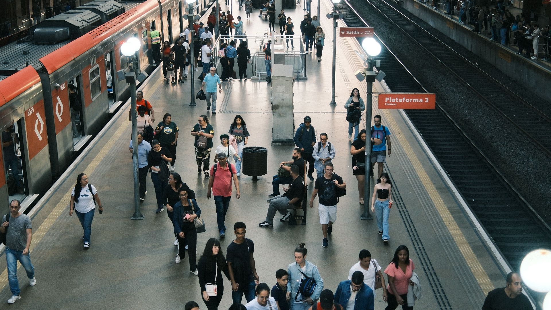 A busy train station with commuters moving through platforms and trains arriving.