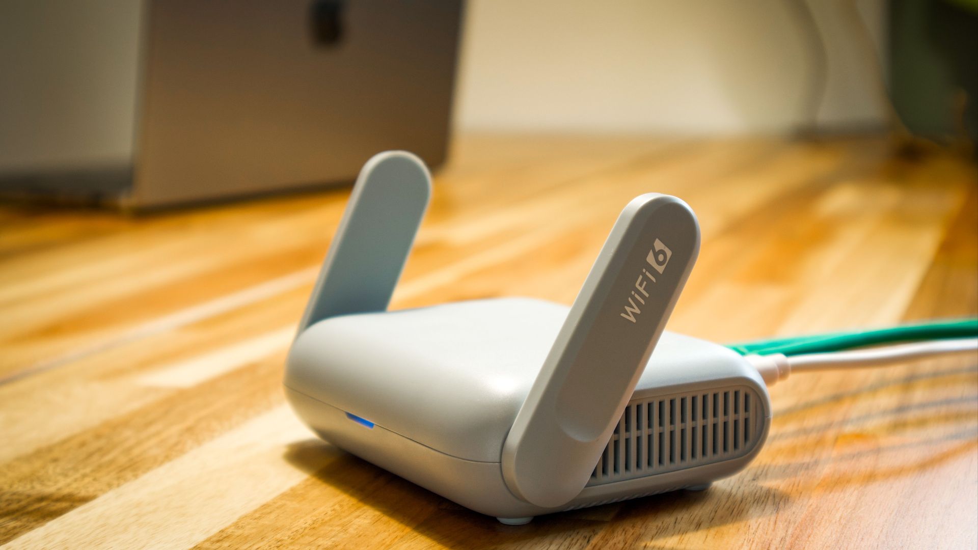 A sleek WiFi 6 router with antennas and cable on a wooden desk, perfect for modern home networks.