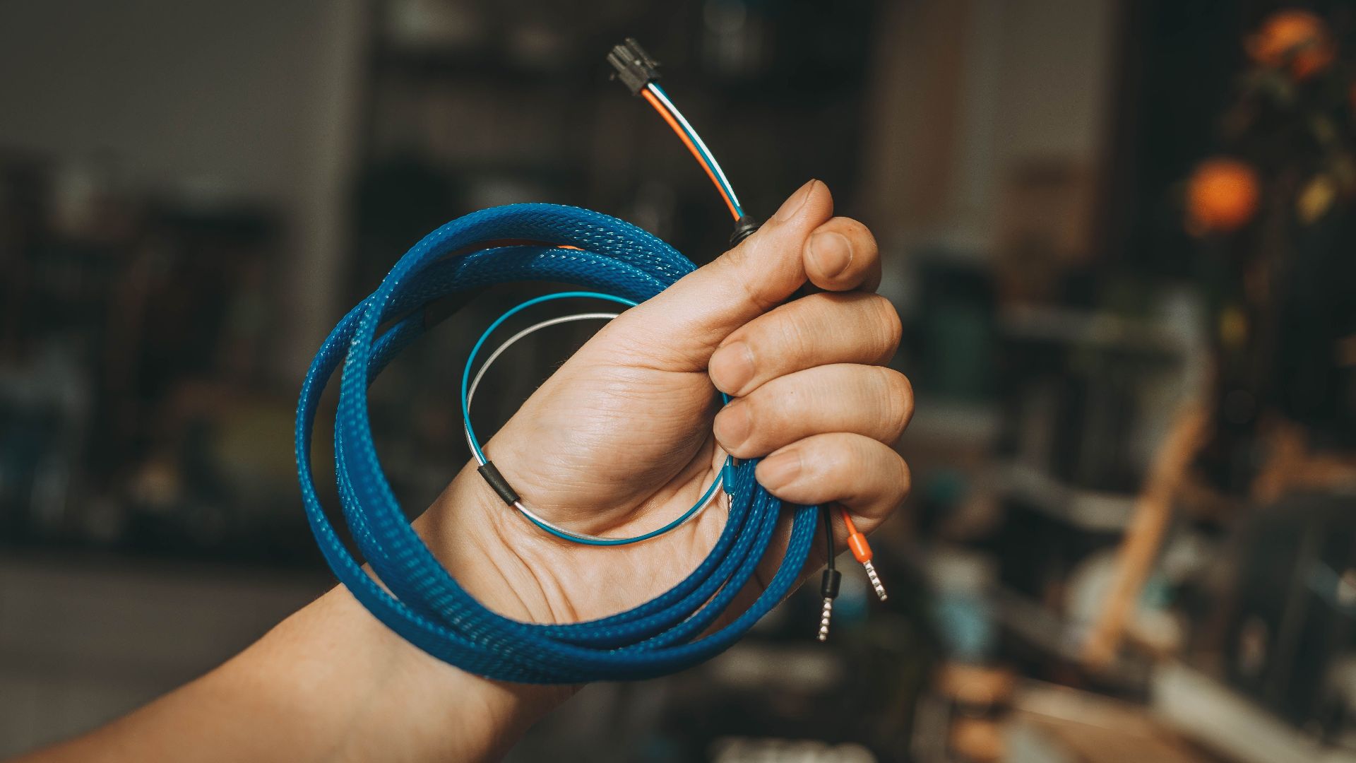 Close-up of a hand holding a coiled blue cable, showcasing a DIY or repair setting.