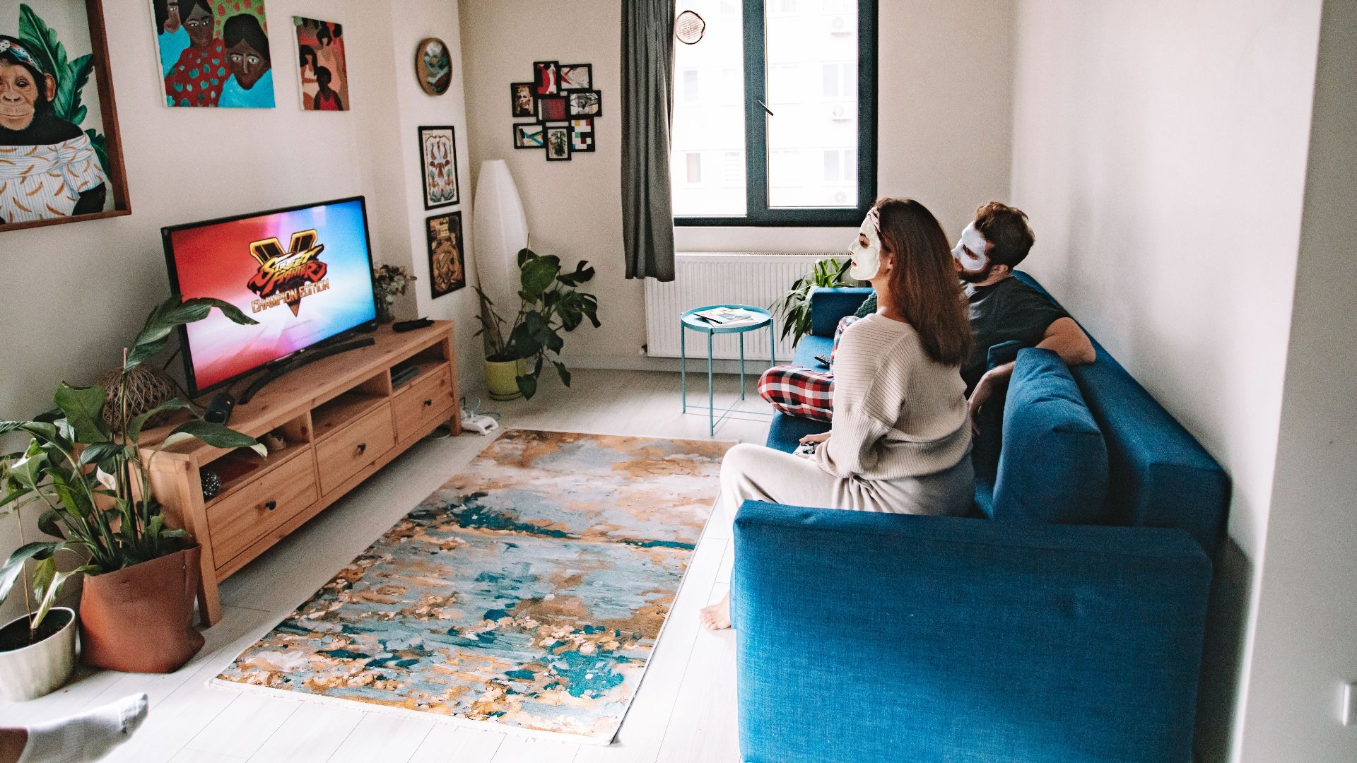 A couple enjoying relaxation time in a stylish living room with indoor plants and TV entertainment.
