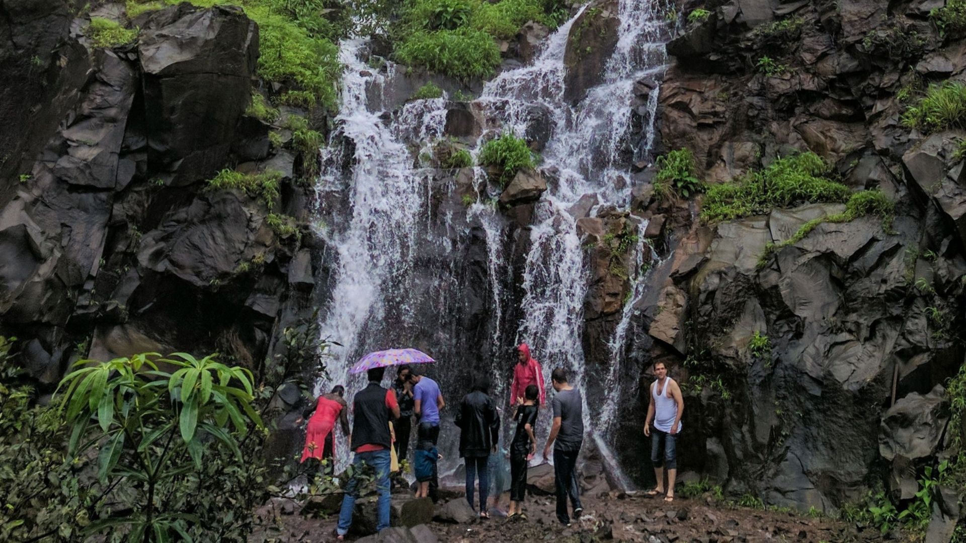 A group of people exploring a waterfall in a misty, rocky environment. Perfect for nature and adventure themes.
