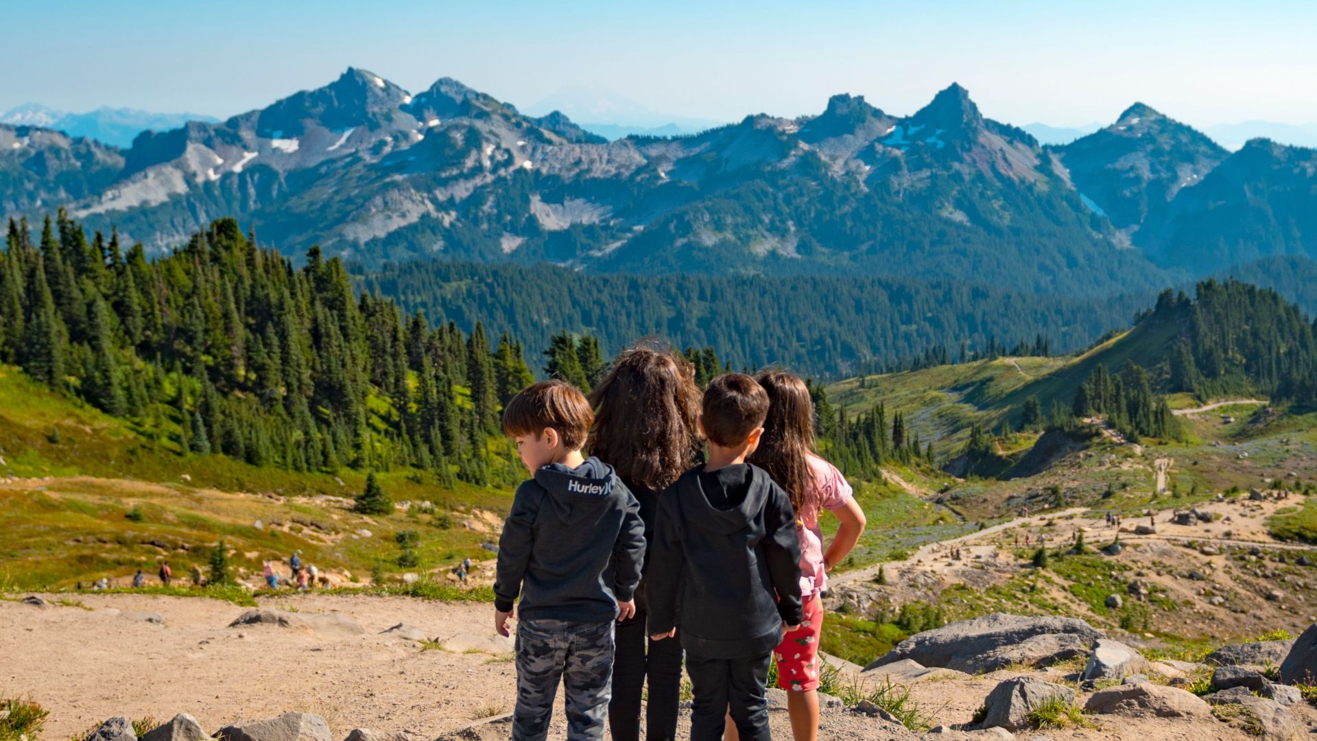 Group of children enjoying a scenic mountain view in a national park on a sunny day.