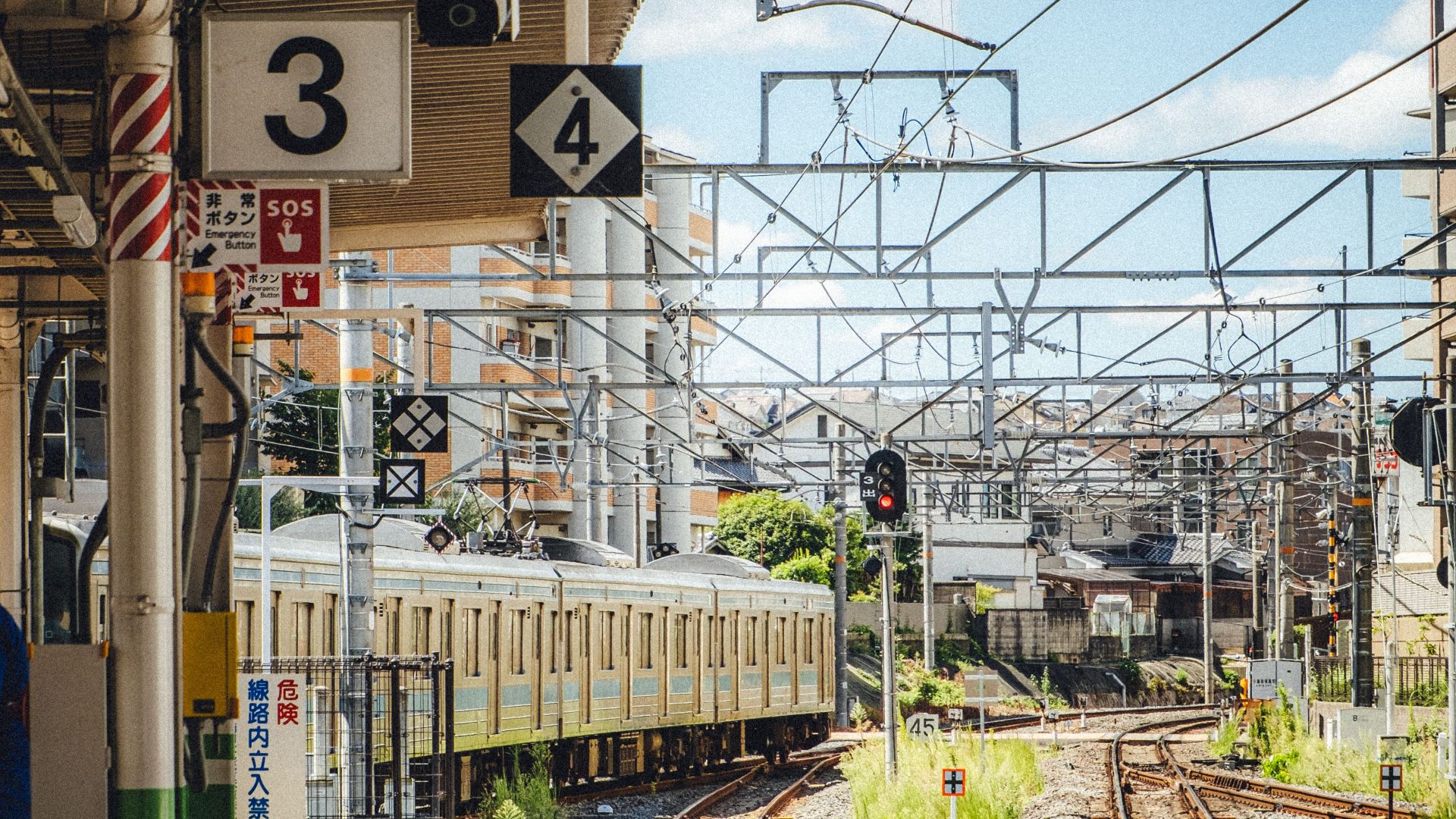 Sunlit train station platform with empty rail tracks. Urban transit scene.