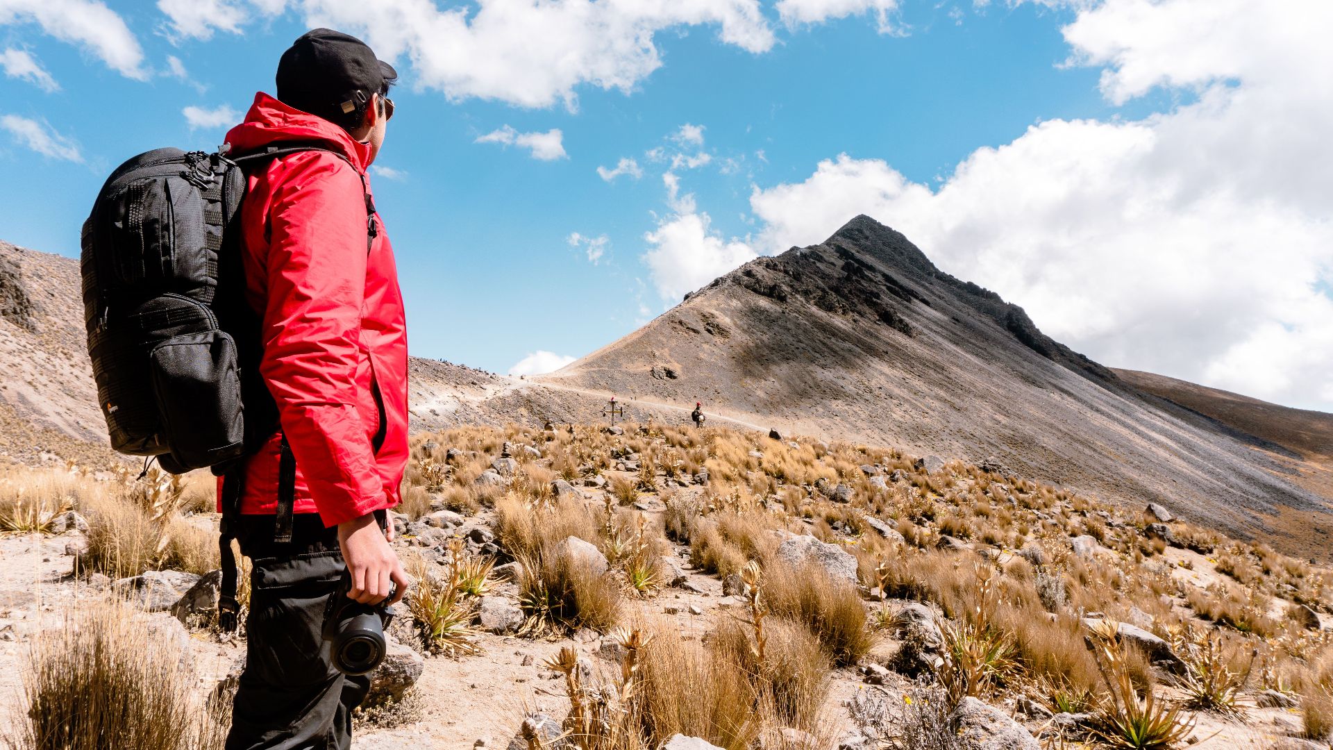 A man in a red jacket hikes on the scenic slopes of Toluca Volcano, México.