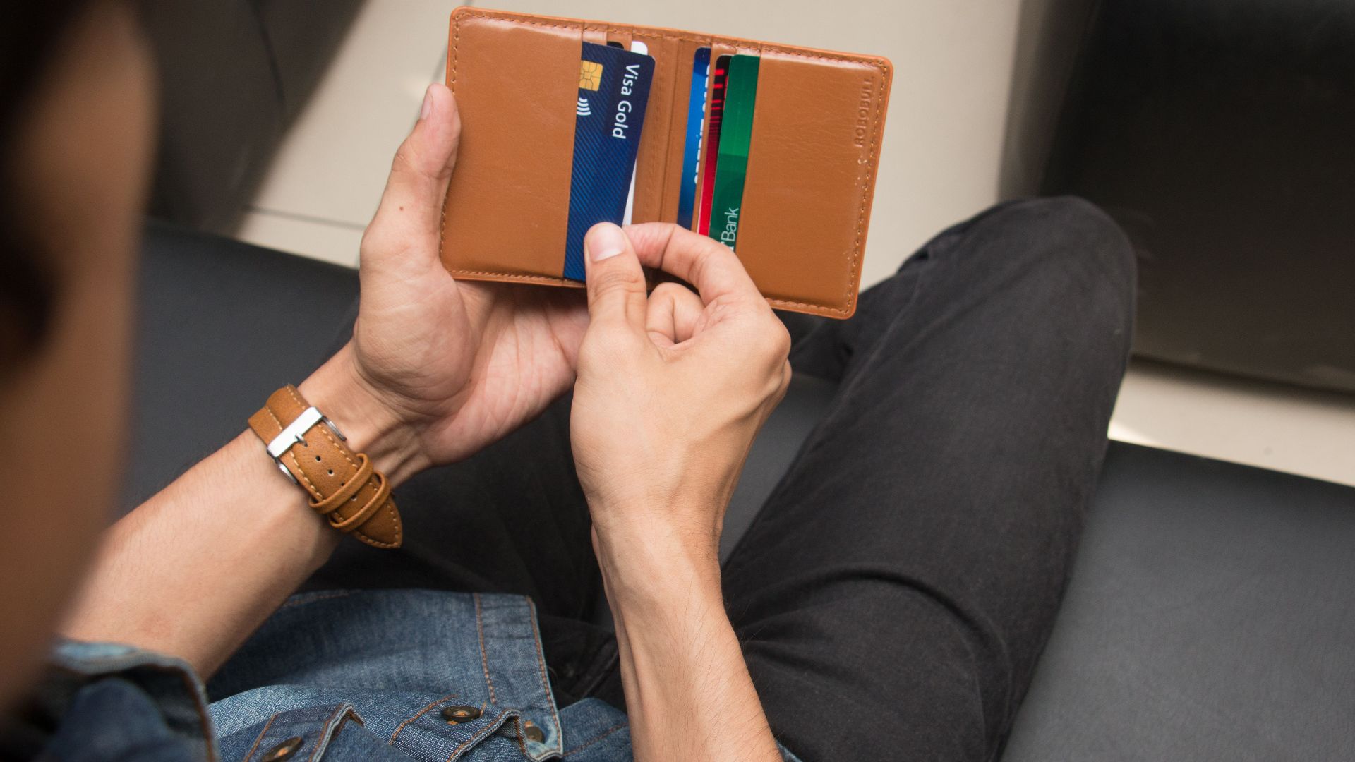 Close-up of a man holding a wallet with various credit cards, showcasing everyday finance essentials.