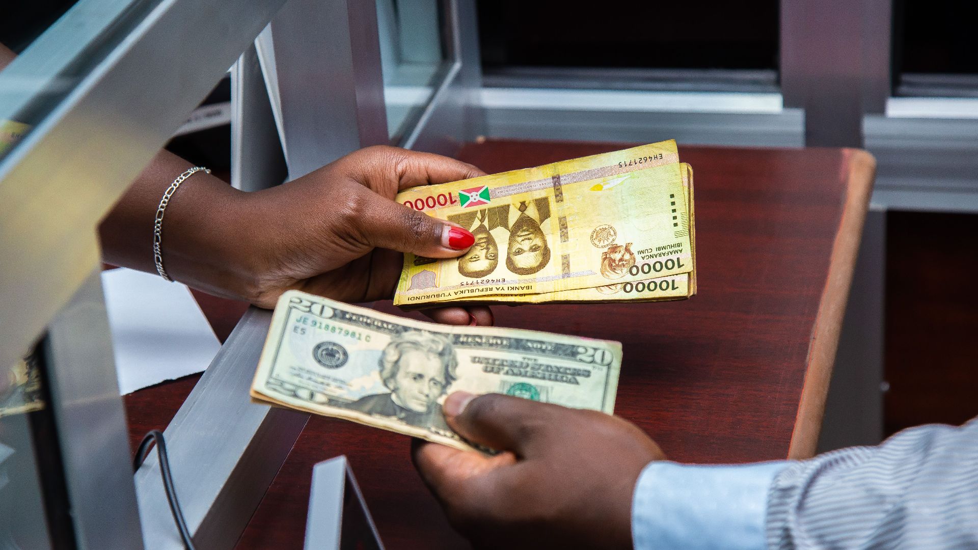 Burundian franc and US dollar exchange transaction at bank counter.
