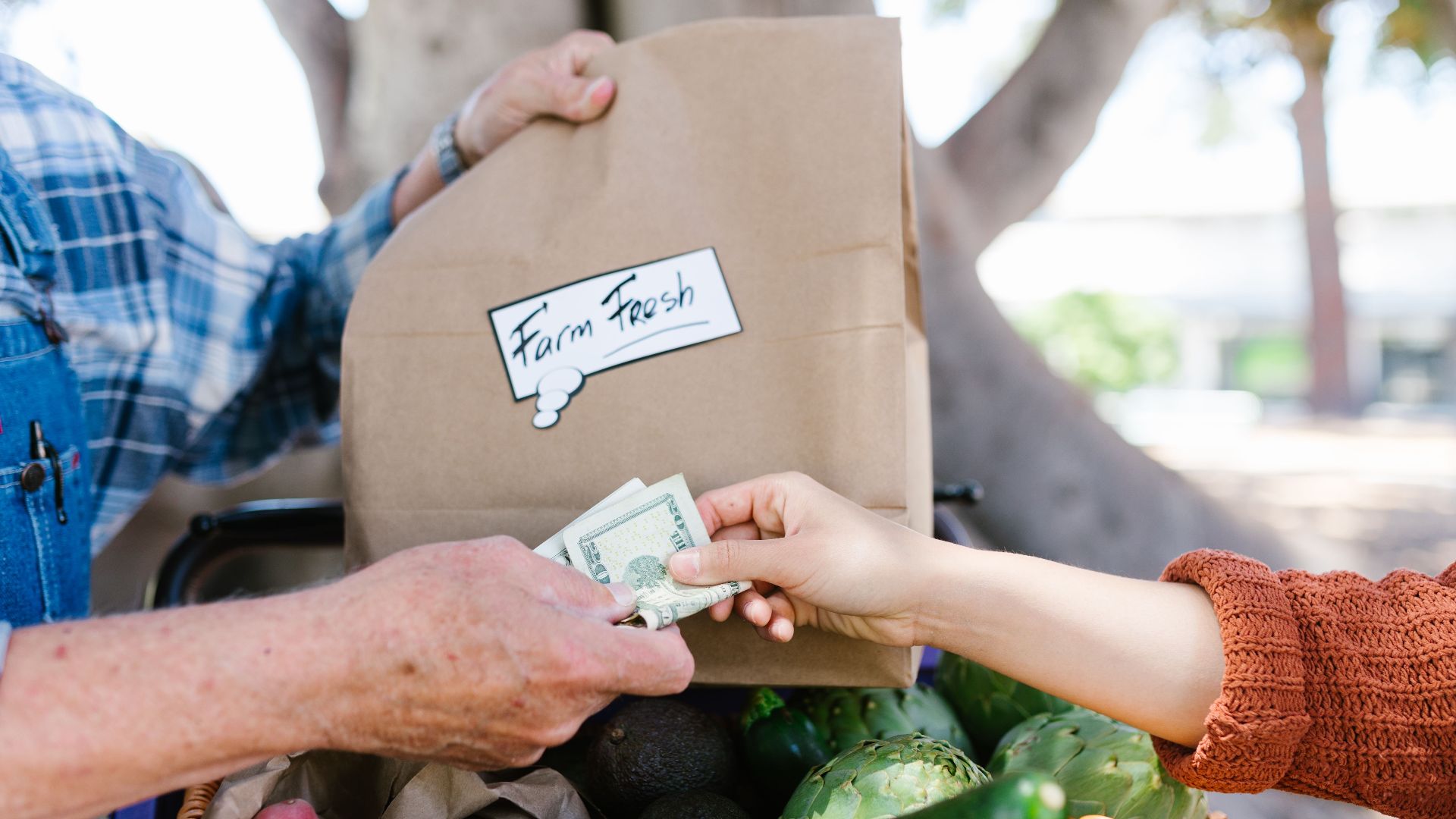 Close-up of a transaction at a farmer's market with fresh produce.