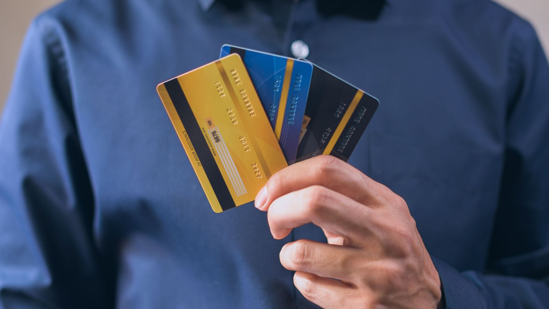 Person holding three credit cards, symbolizing finance, security, and e-commerce.