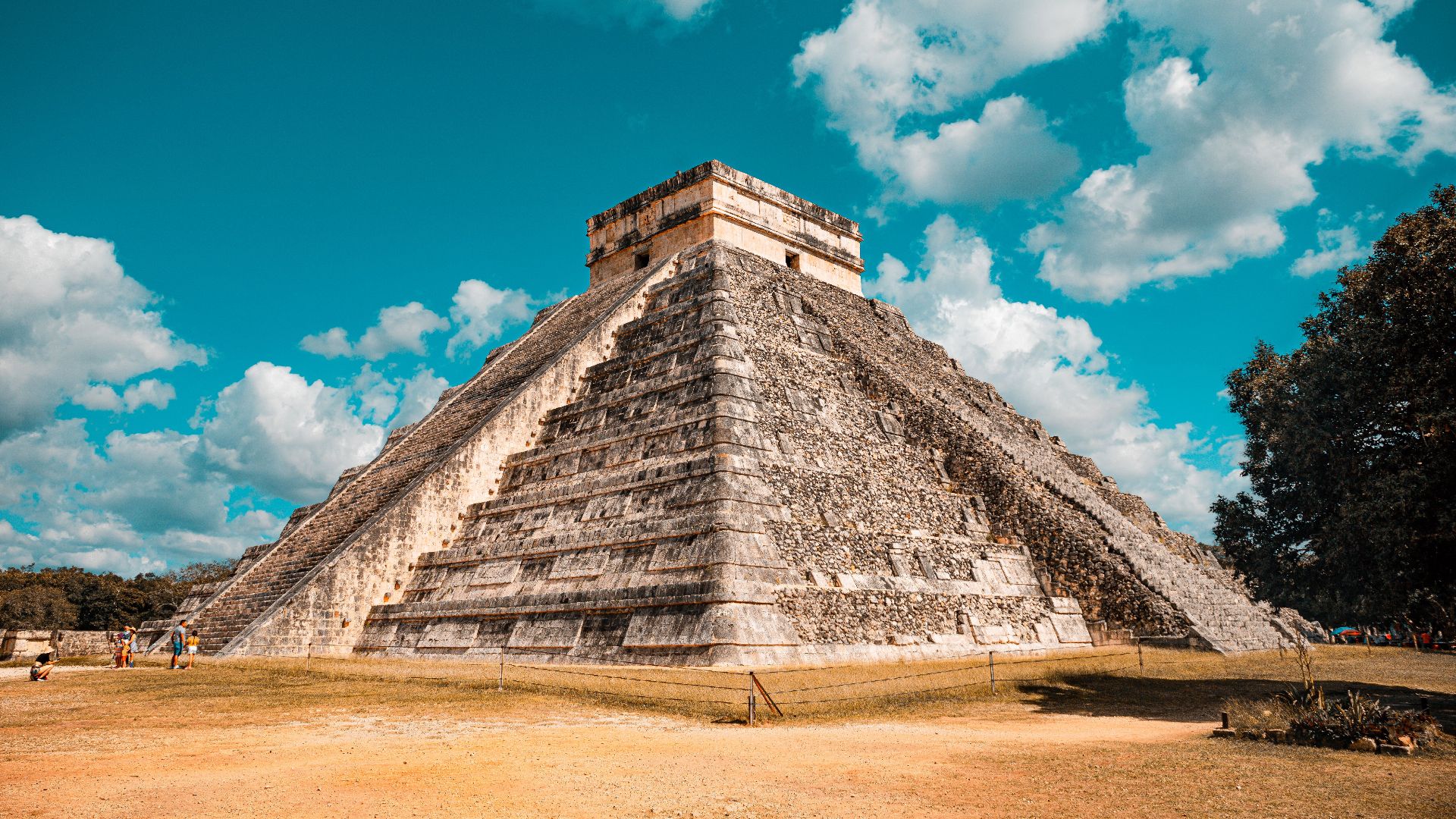 The iconic El Castillo pyramid at Chichen Itza, Mexico, captured on a sunny day with a vibrant blue sky.