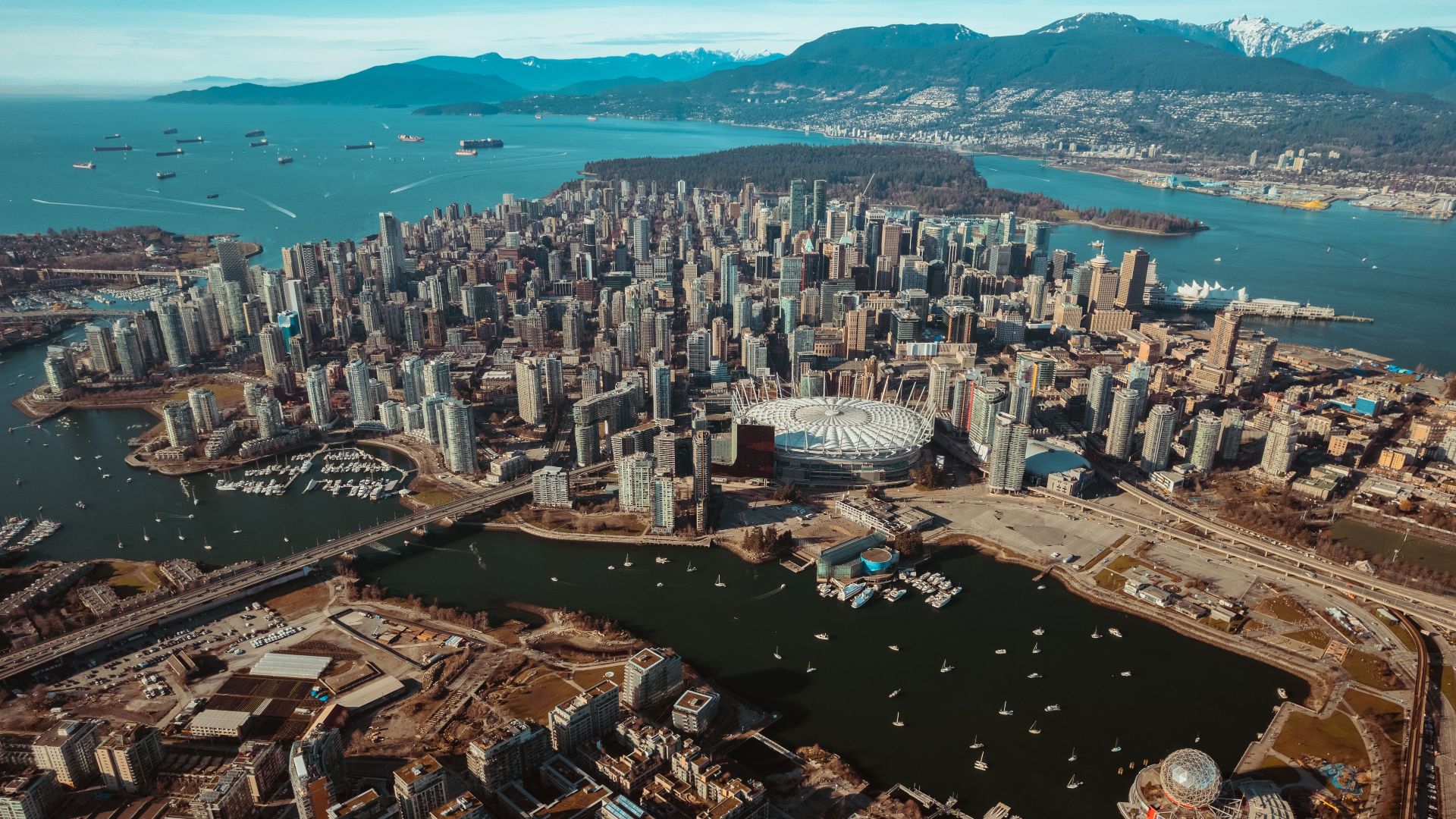 Stunning aerial view of Vancouver's cityscape, showcasing skyscrapers and coastal mountains.
