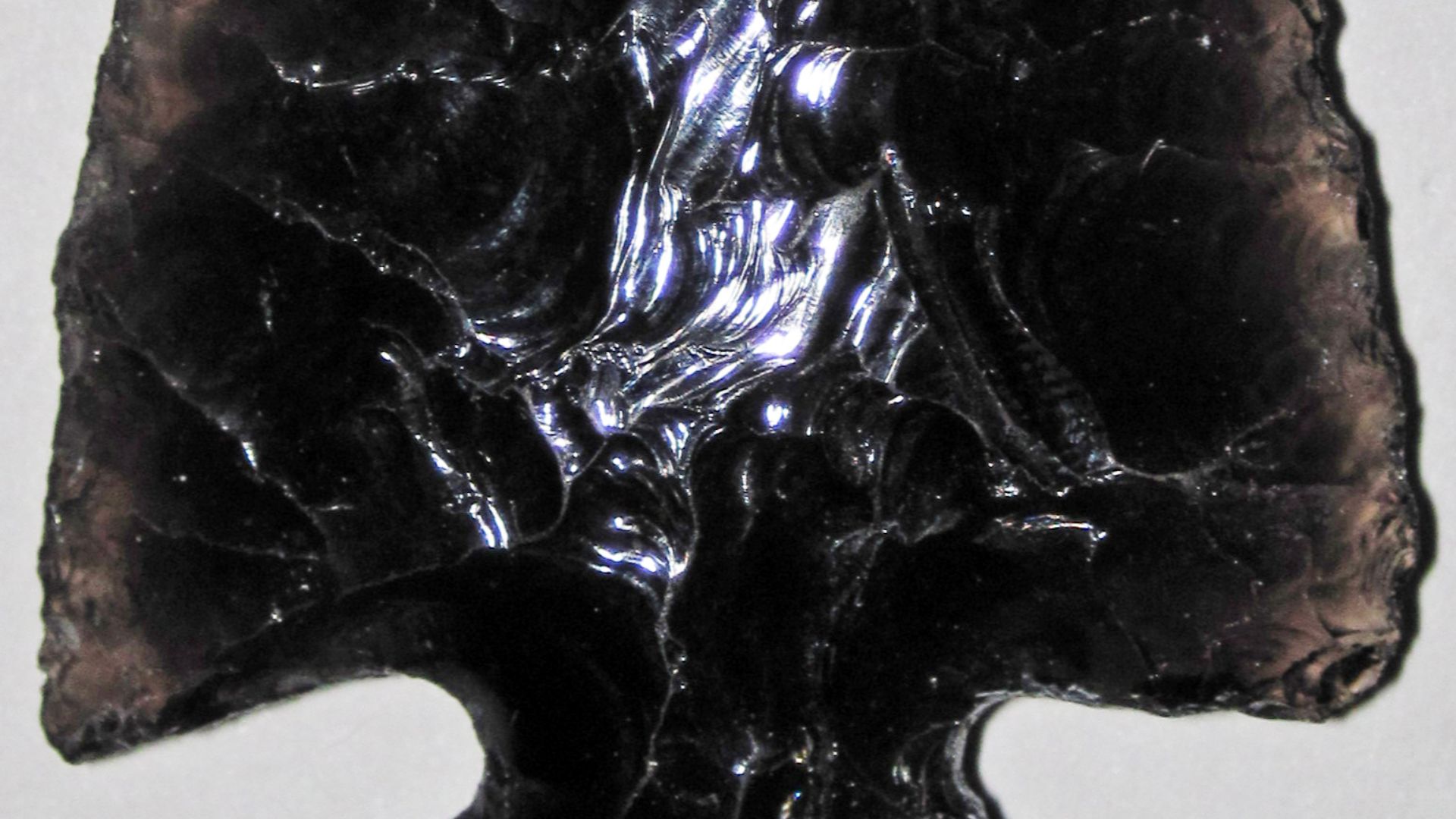 Obsidian-knapped arrowhead. (~6.2 centimeters from top to bottom)
Knapper: John Bohan
Obsidian is a glassy-textured, extrusive igneous rock.  It forms by either very rapid cooling of lava or by cooling of high-viscosity lava.  The latter origin is the mos