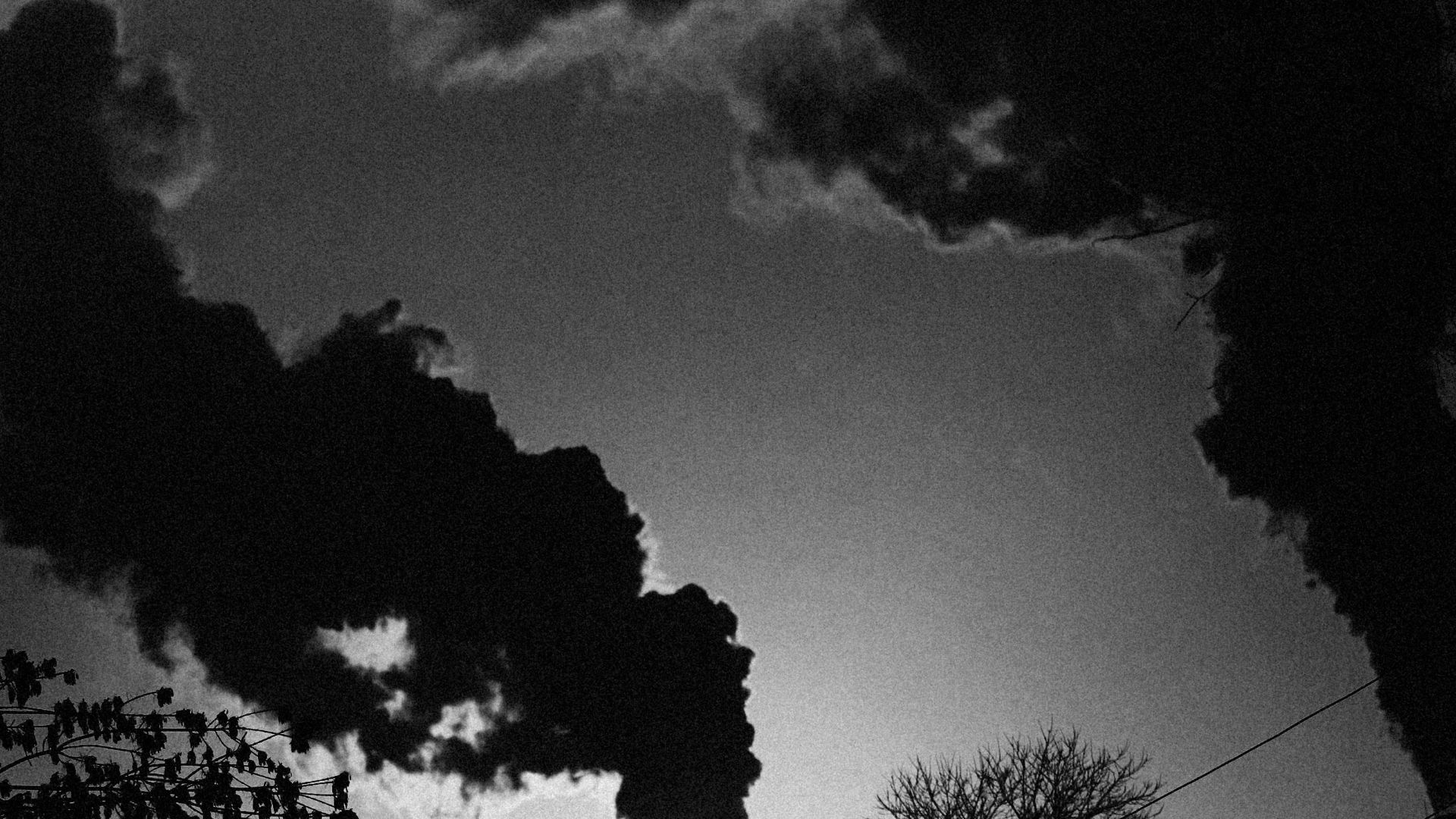 a black and white photo of smoke coming out of a factory