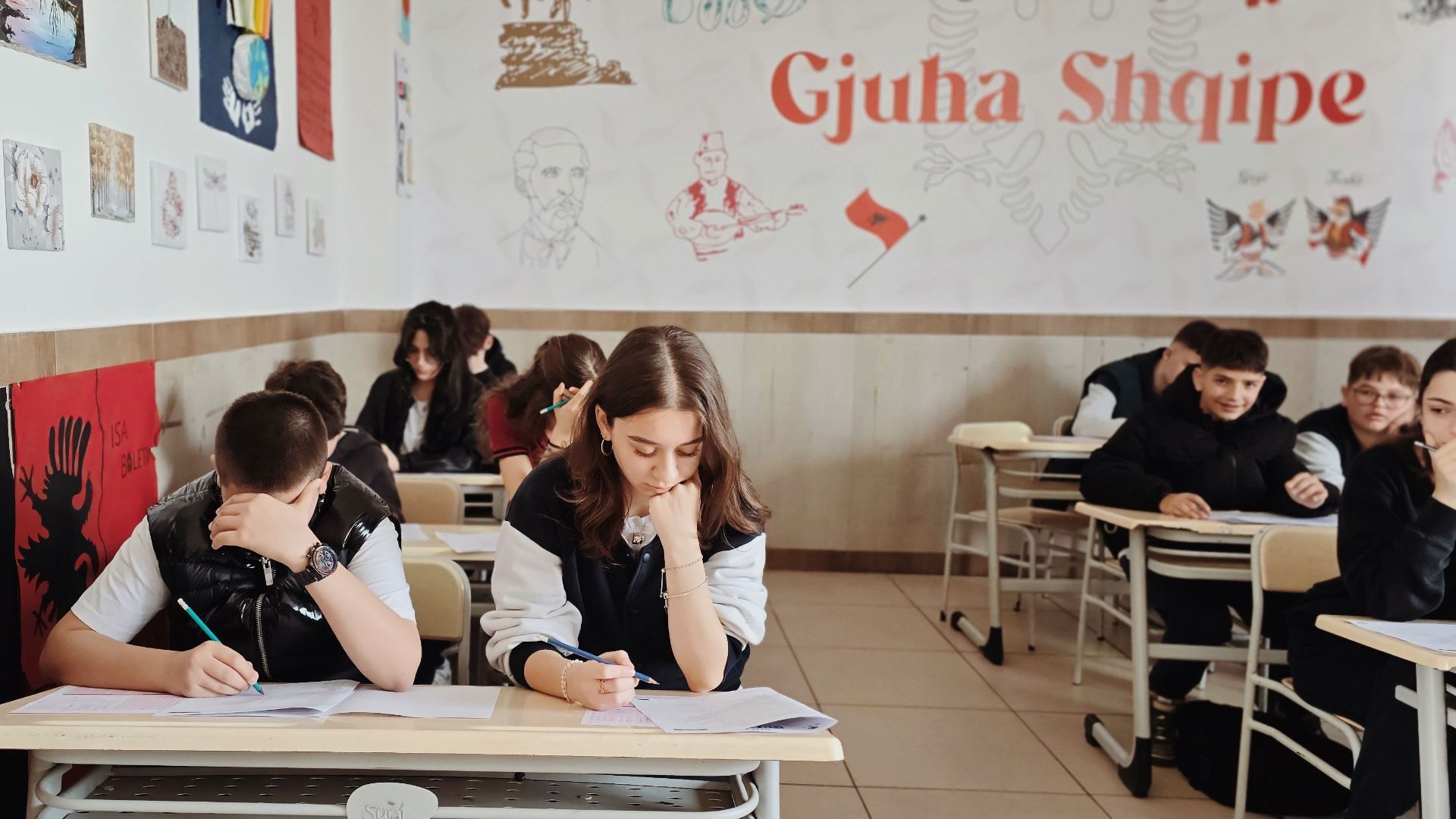 Teenagers focusing on studies in an education setting with Albanian motifs.