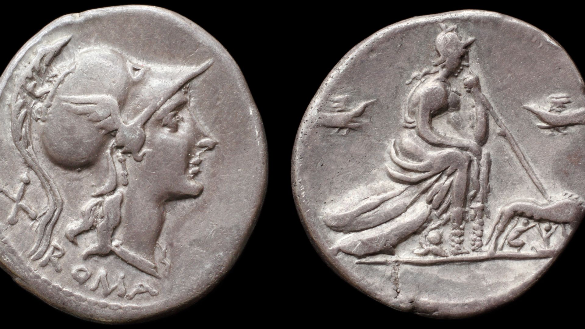 Obverse: X (mark of value) / ROMA
head of Roma right wearing winged Corinthian helmet
Reverse:
Roma seated right on pile of shields, wearing Corinthian helmet, holding spear, helmet at feet; she-wolf sucling Romulus and Remus to the right; birds on either