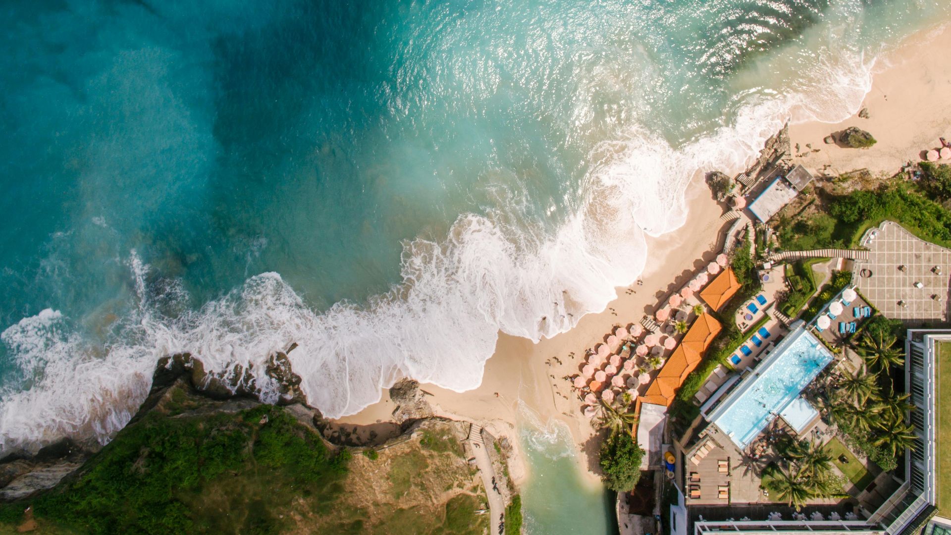 Aerial view of a beautiful beach resort with turquoise waters and sandy shores.