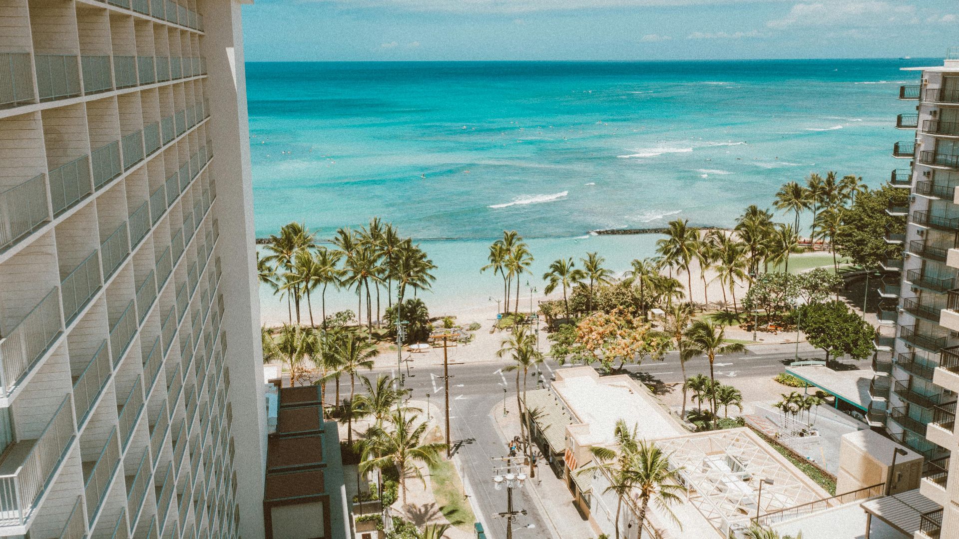 Breathtaking view of Waikiki Beach and palm trees from a hotel balcony in Honolulu, Hawaii.