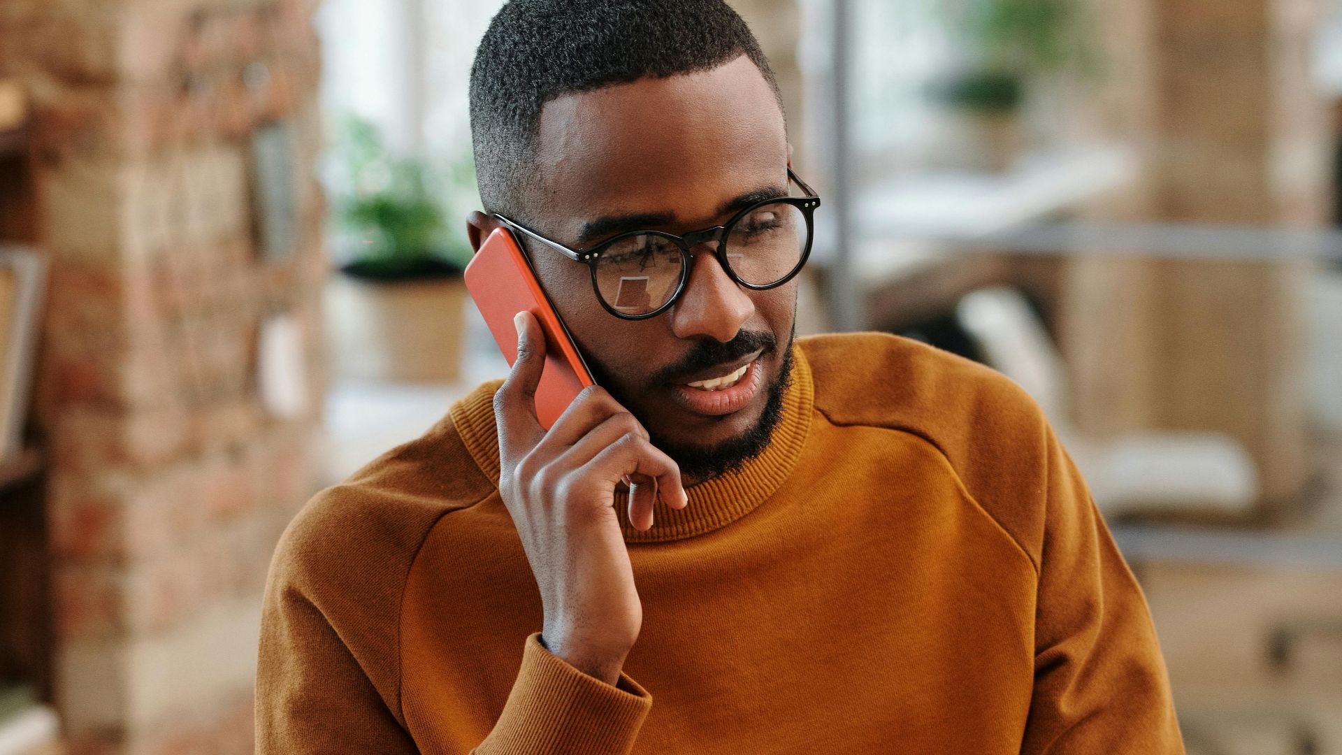 Young man in a modern office multitasking with a digital tablet and mobile phone.