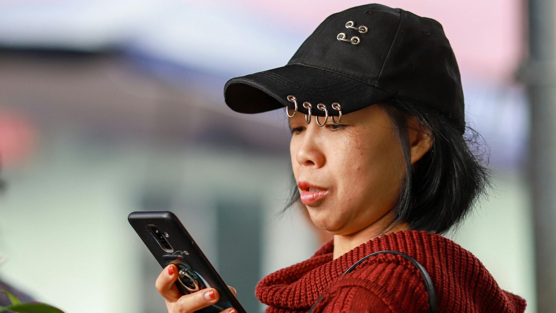 A woman using her smartphone while shopping at the vibrant Lào Cai market in Vietnam.