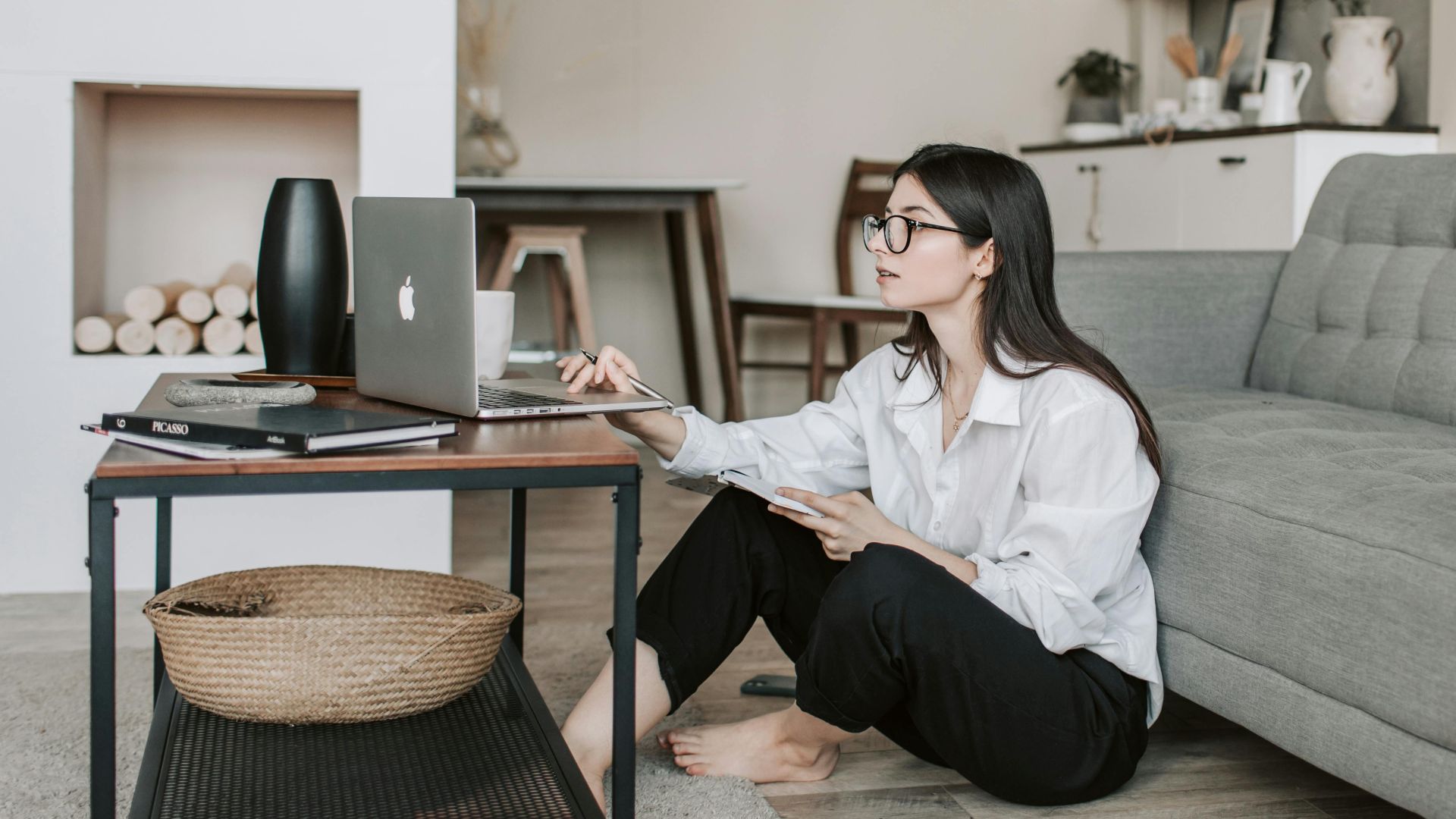 Asian woman working on laptop from cozy living room, showcasing modern home office setup.