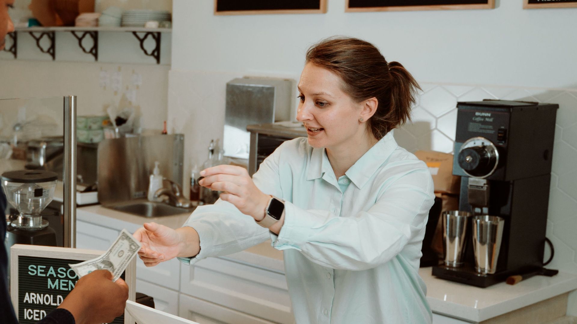 A customer pays for coffee at a café counter, transaction with barista.