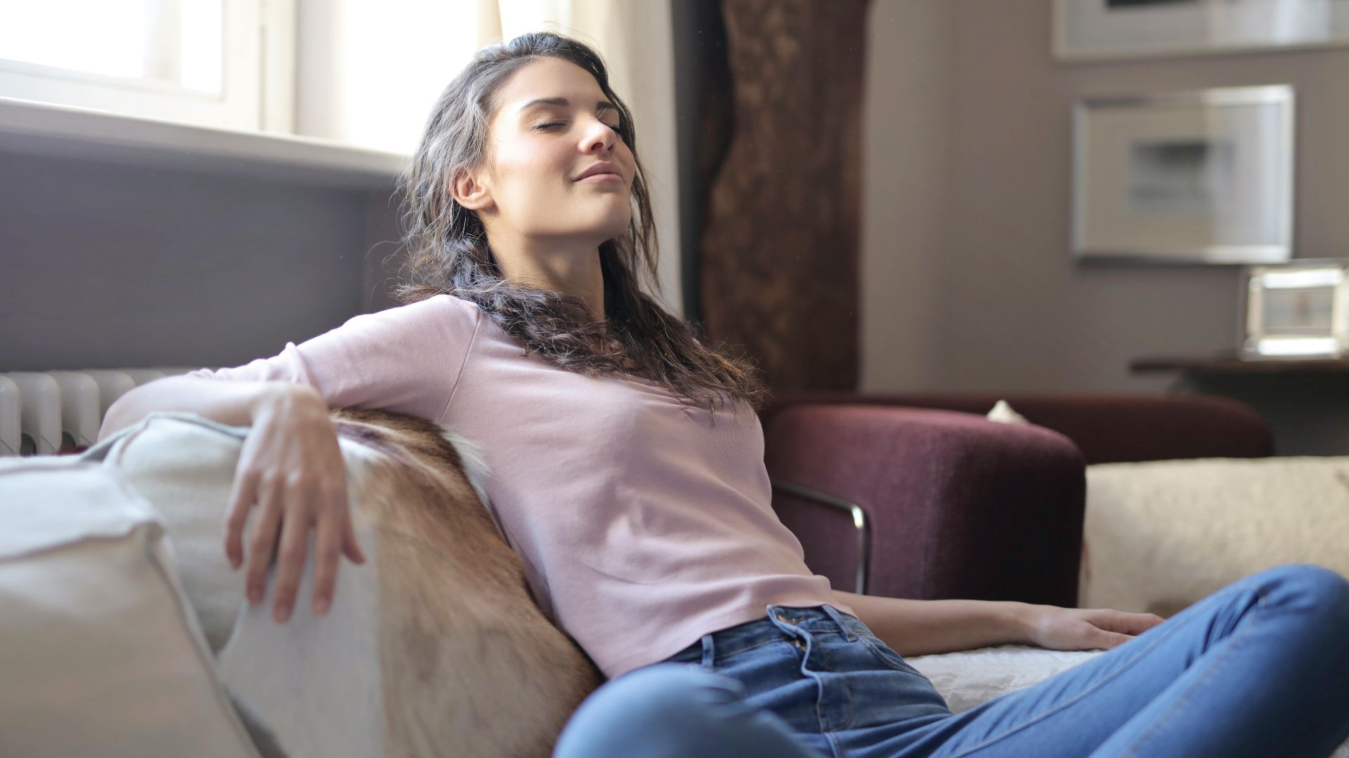 Woman relaxing on a couch in a cozy living room, embodying tranquility and comfort.