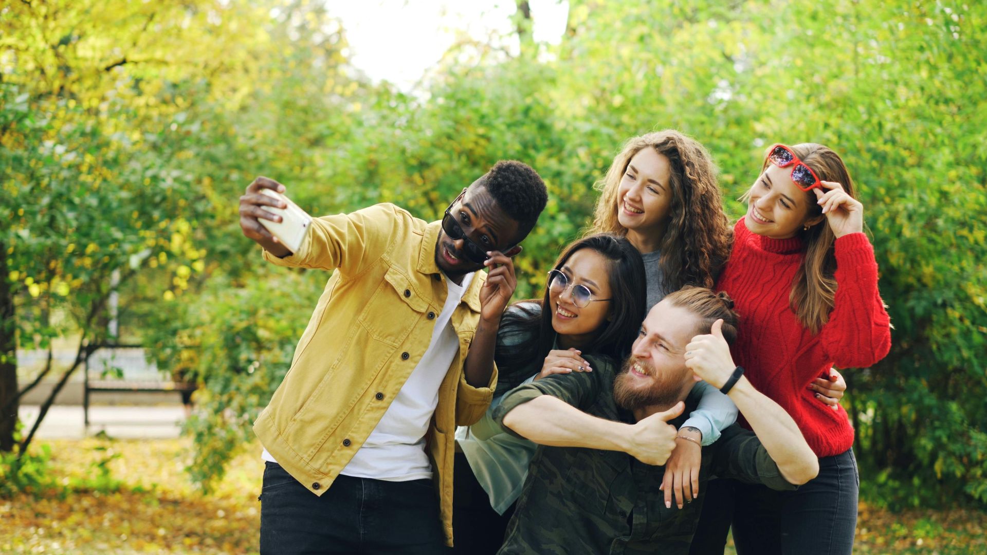Group of diverse friends taking a selfie in a park during autumn.