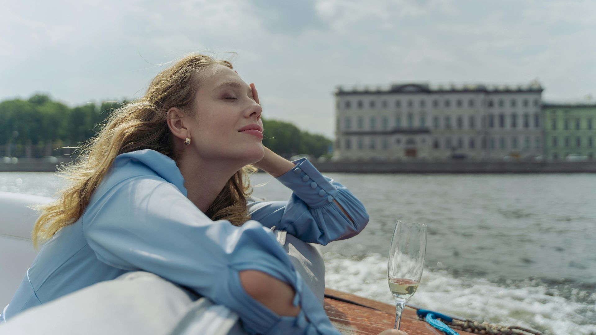 Woman enjoying a serene boat trip with a glass of white wine in Saint Petersburg.