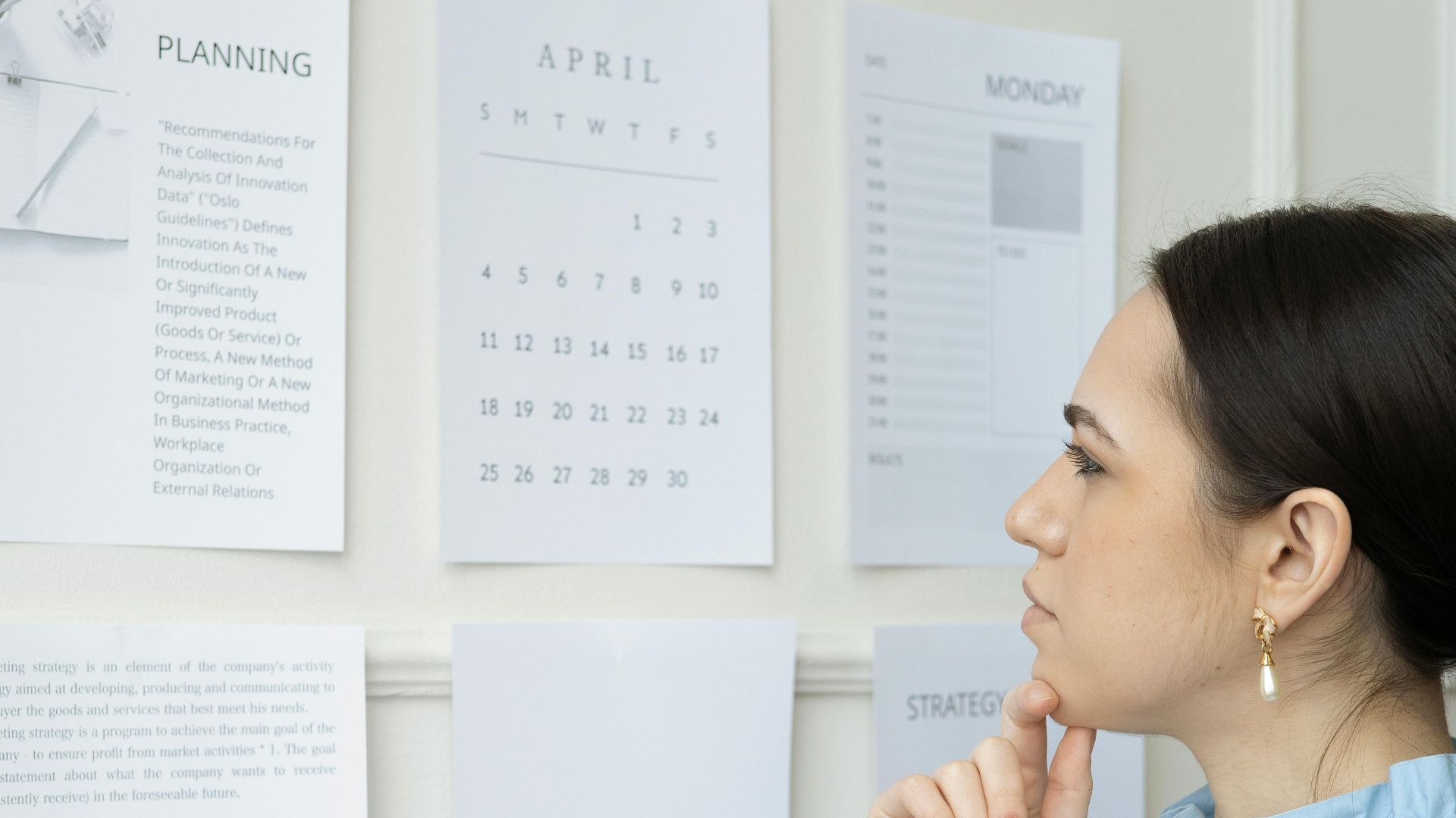 Businesswoman strategizing branding and planning at office wall with papers and calendar.