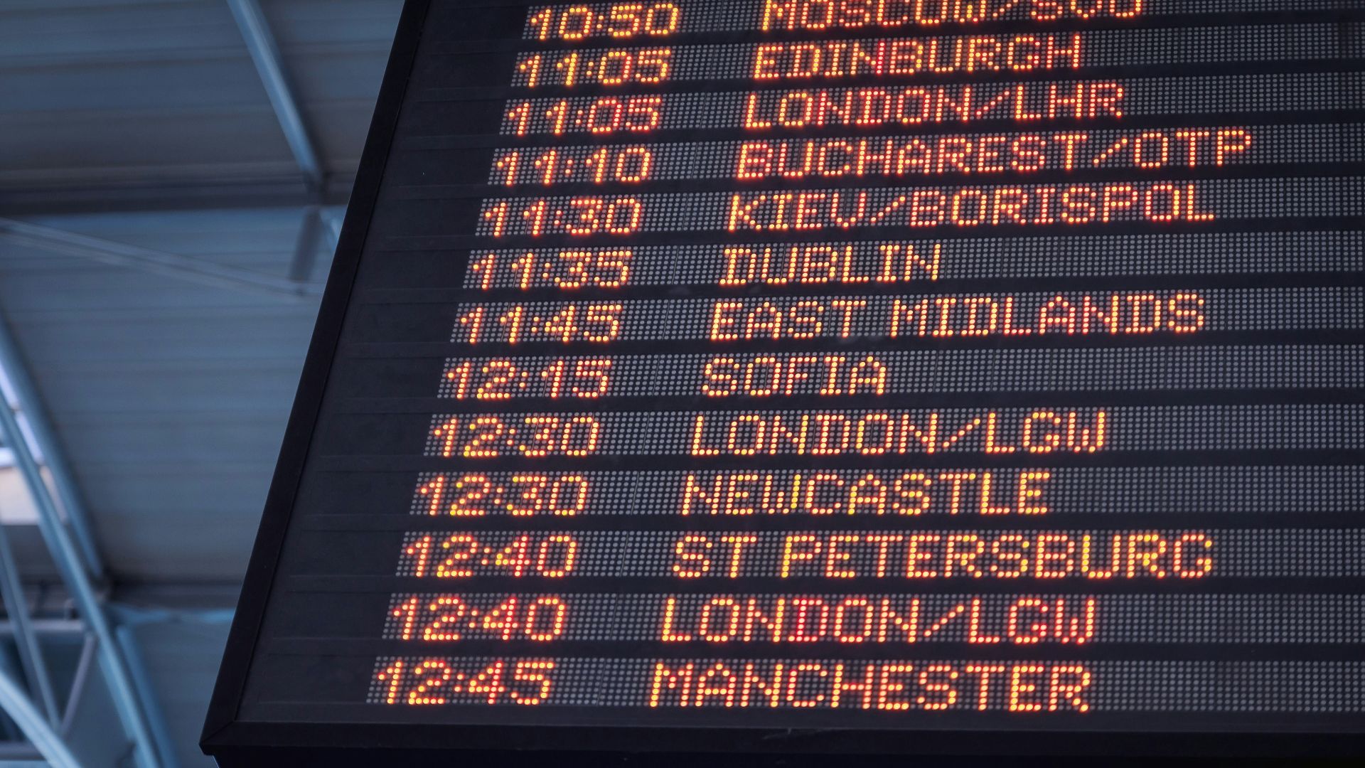 A low-angle shot of a departure board at an airport