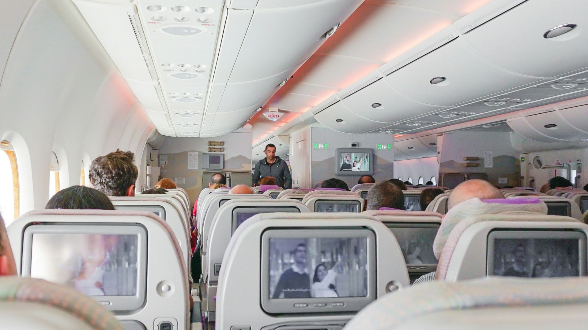 man walking down the aisle of airplane