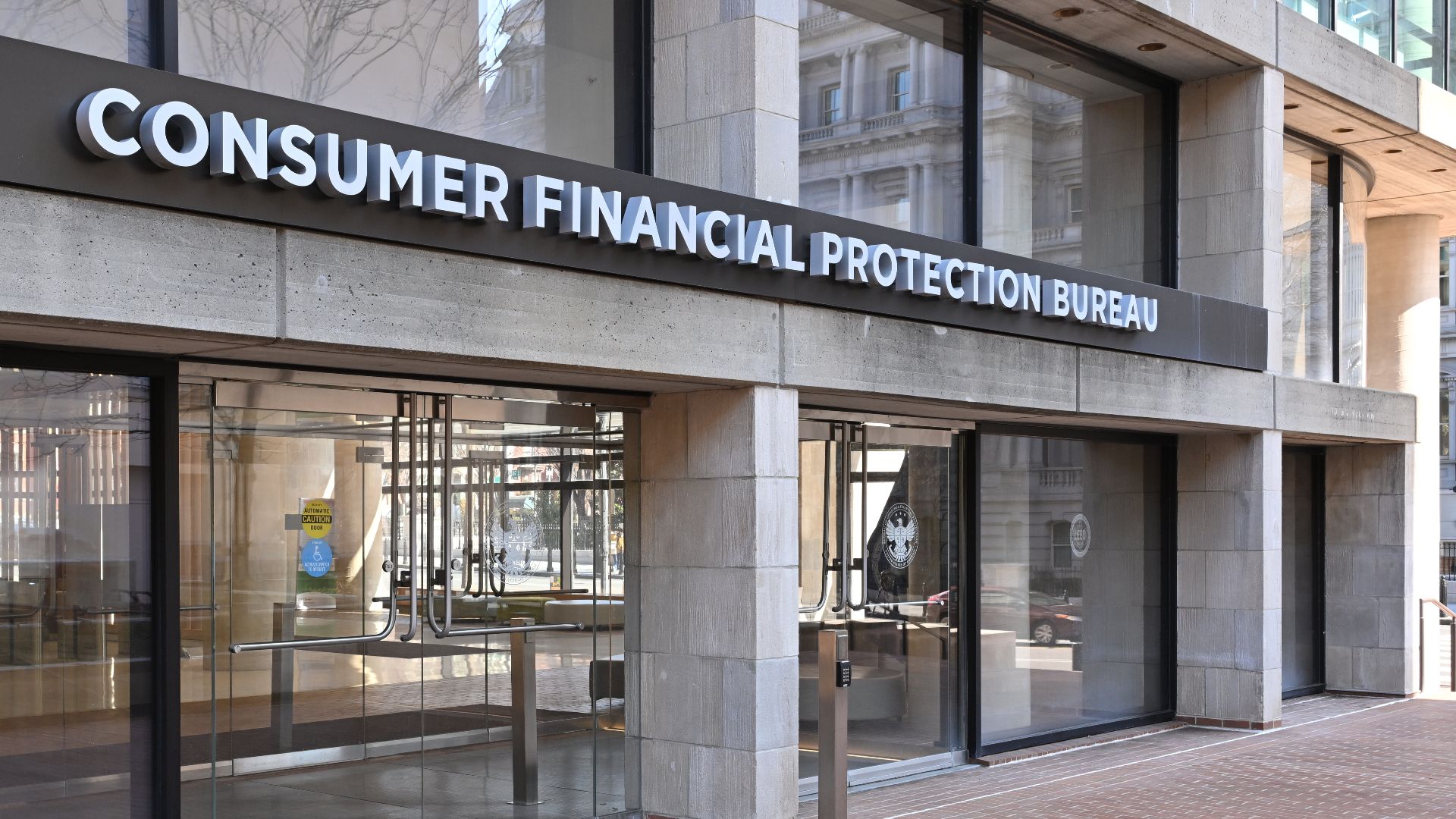 The entrance to the Consumer Financial Protection Bureau headquarters with the bureau's name above it. 1700 G Street NW, Washington, DC 20552.