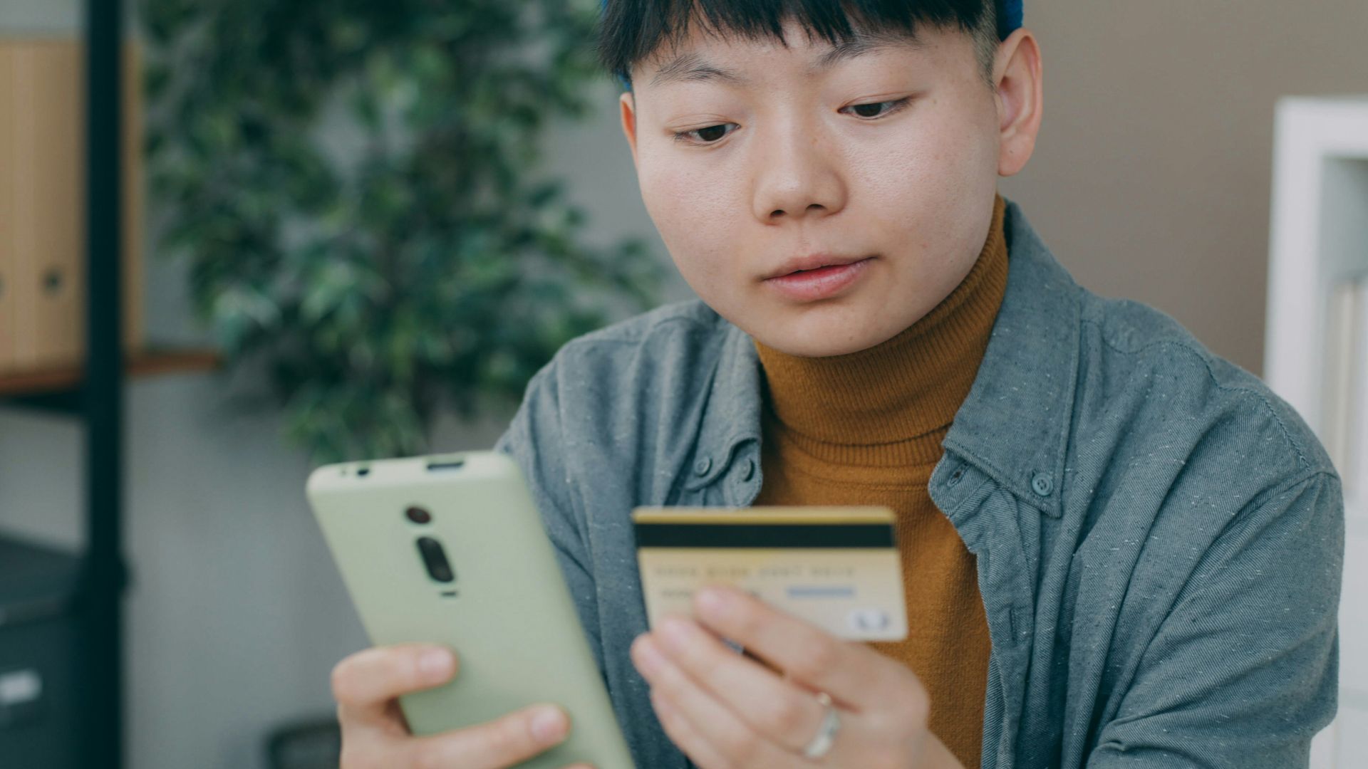 A man sitting at a table looking at a cell phone