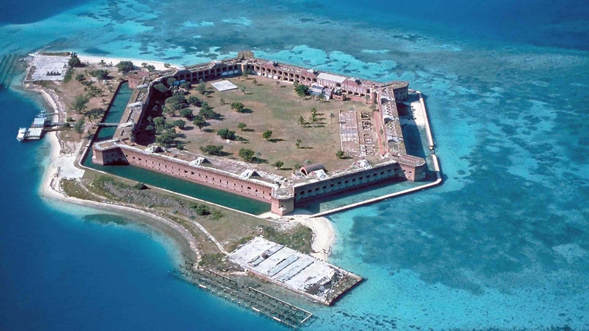 Fort Jefferson at the Dry Tortugas. The clear waters in shallow areas surrounding the fort, seen easily in the photo, are popular for snorkeling and scuba diving. Visible on the right side of the image is a breach of the sea wall caused by the direct stri