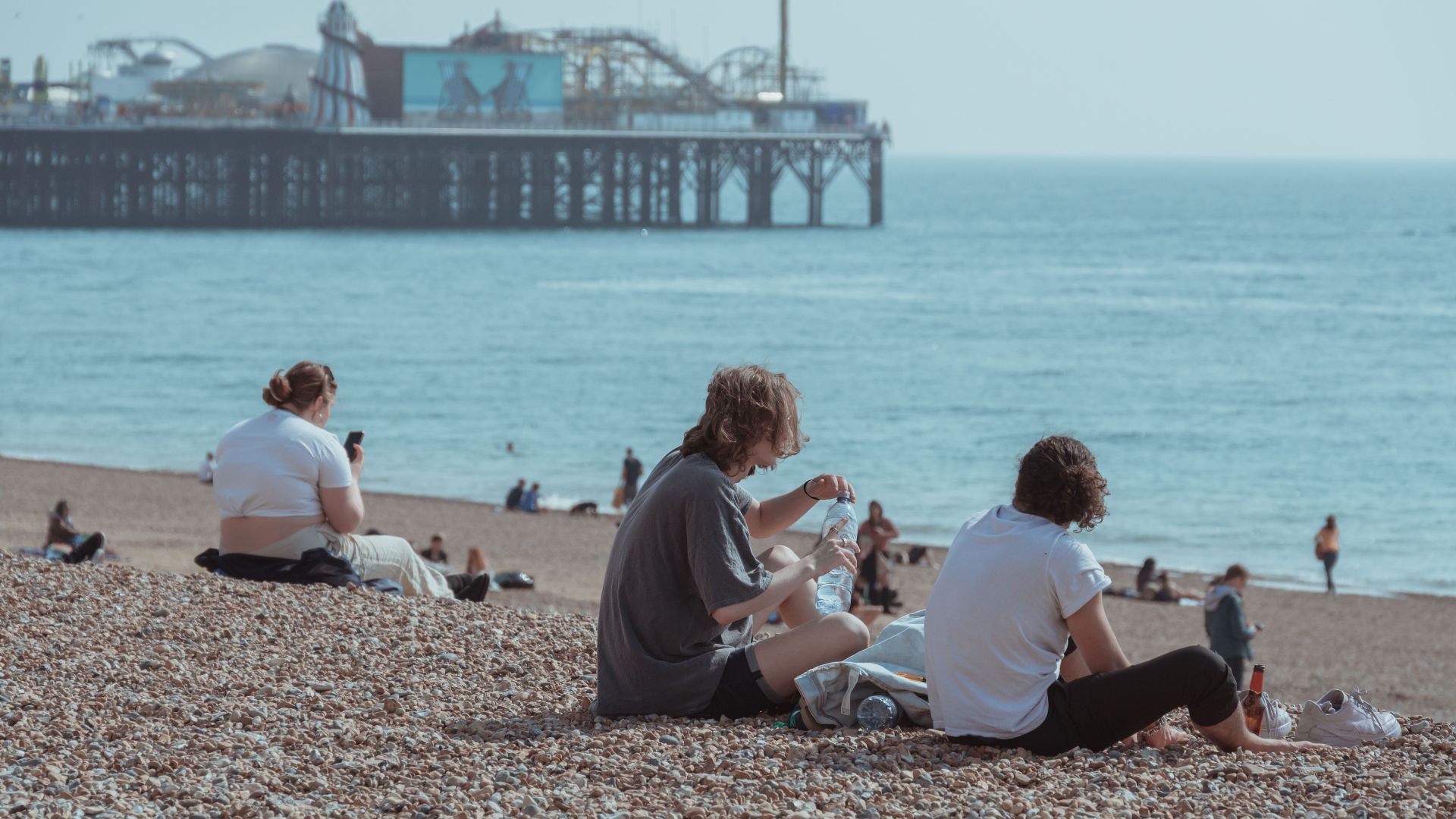People enjoying a sunny day at Brighton Beach with the iconic pier in the background.