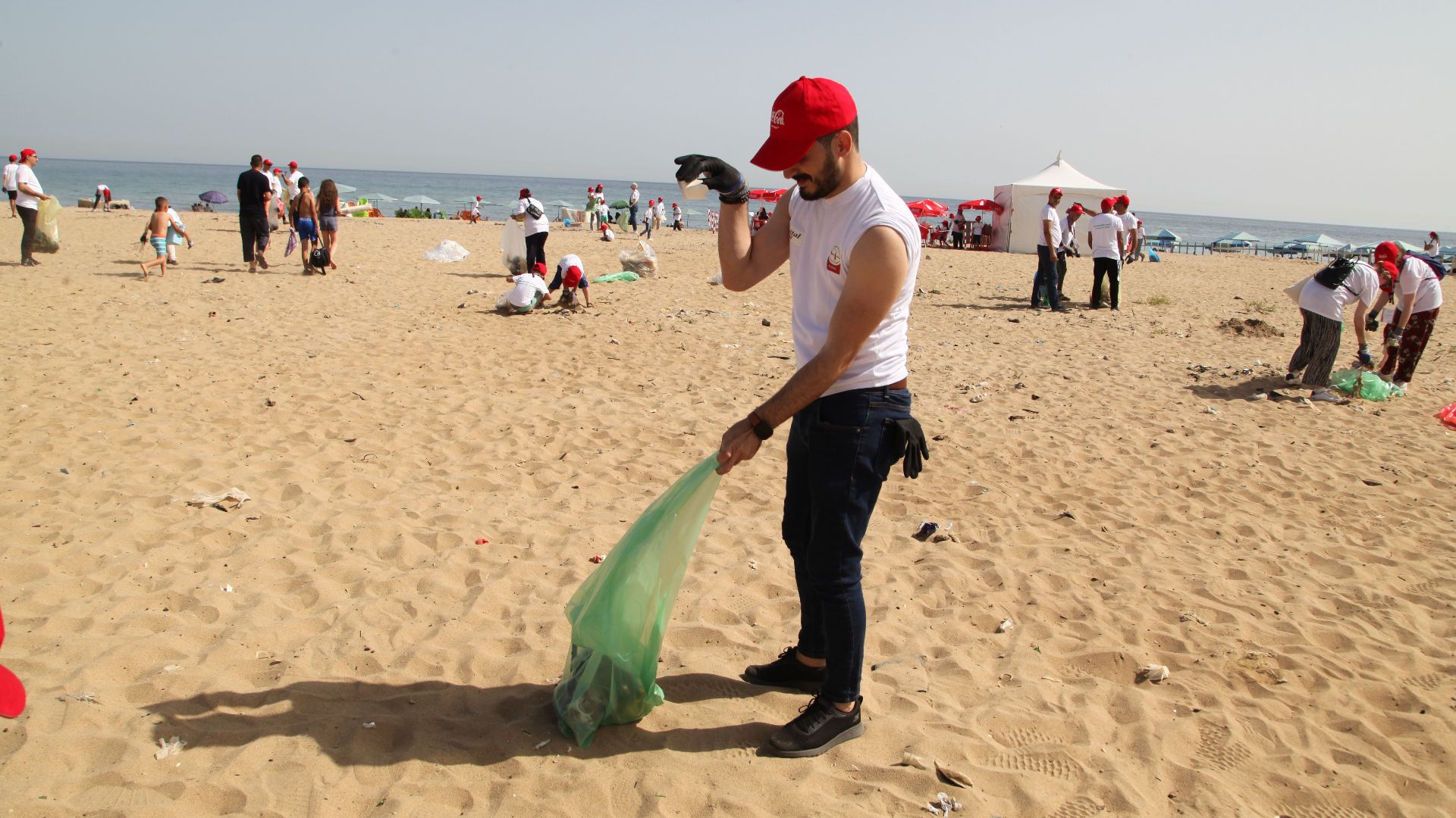 Volunteers cleaning up beach in Algiers, promoting environmental awareness.