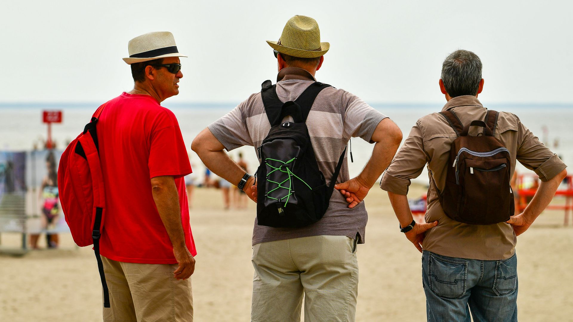 Three men in summer attire enjoying a sunny day at Pärnu Beach, Estonia.