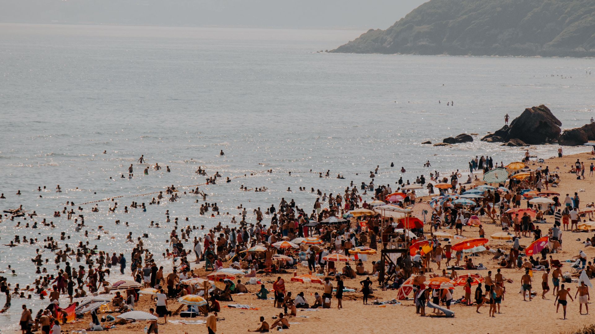 Crowded summer beach at Kilyos, İstanbul with swimmers and umbrellas.