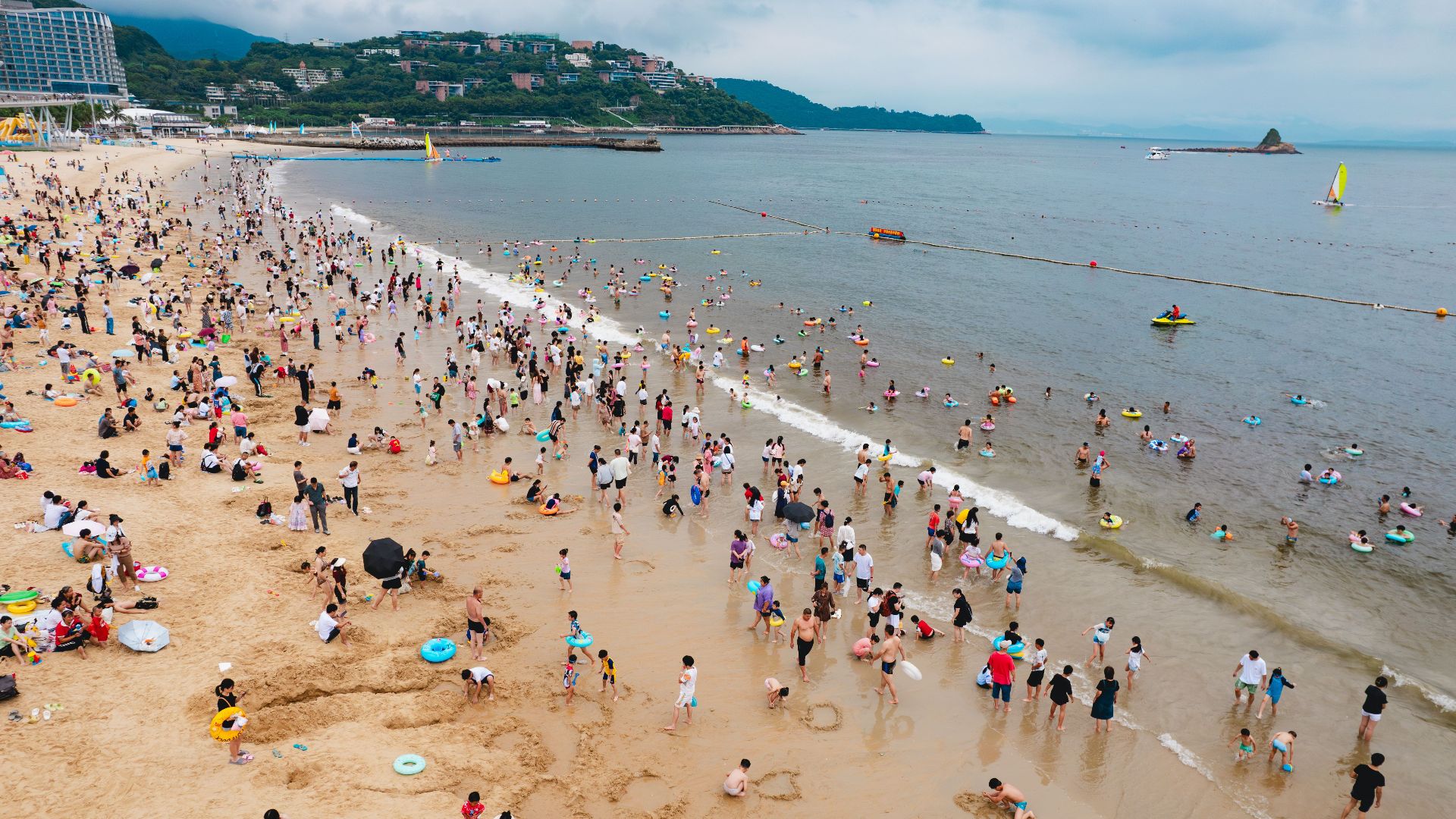 A lively summer scene at the beach in Shen Zhen Shi with crowds enjoying the seaside.