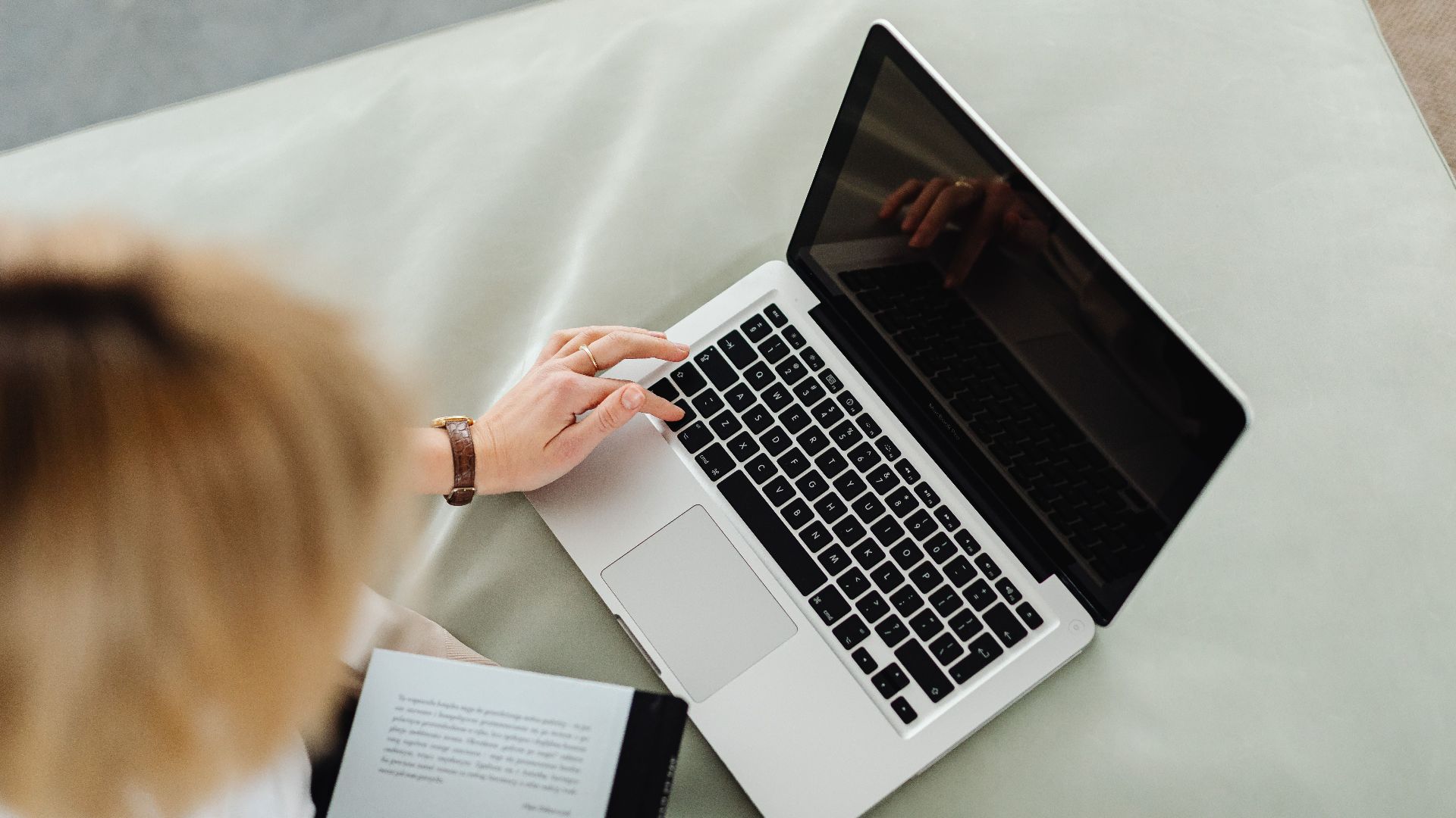 A woman uses a laptop while sitting inside, illustrating remote work lifestyle.