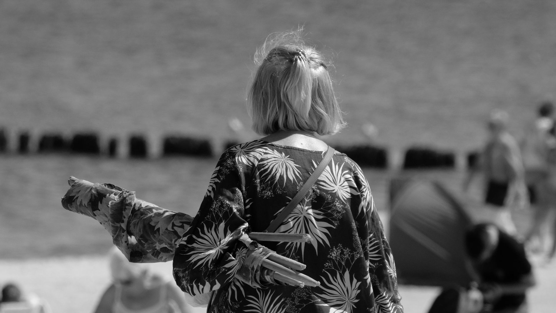 Monochrome photo captures a calm beach scene with people enjoying a day outdoors.