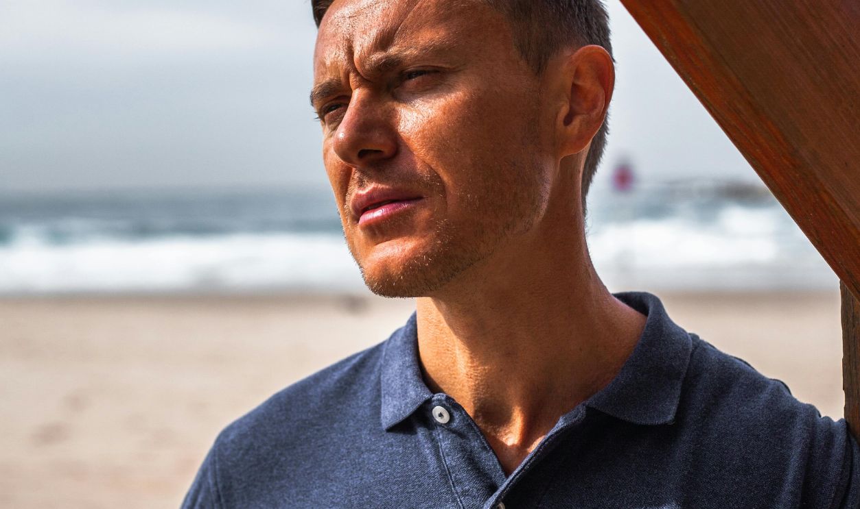 A thoughtful man in a polo shirt stands by the sea in Tel Aviv, Israel